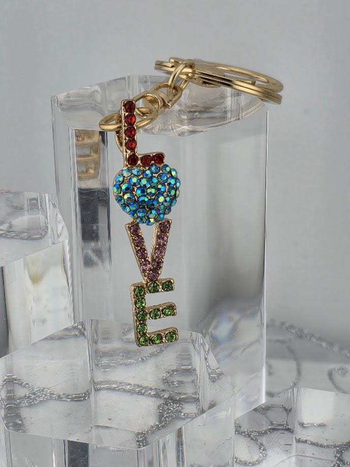 A pink gift box with a keychain attached to it, featuring a colorful charm in the shape of the word "LOVE".