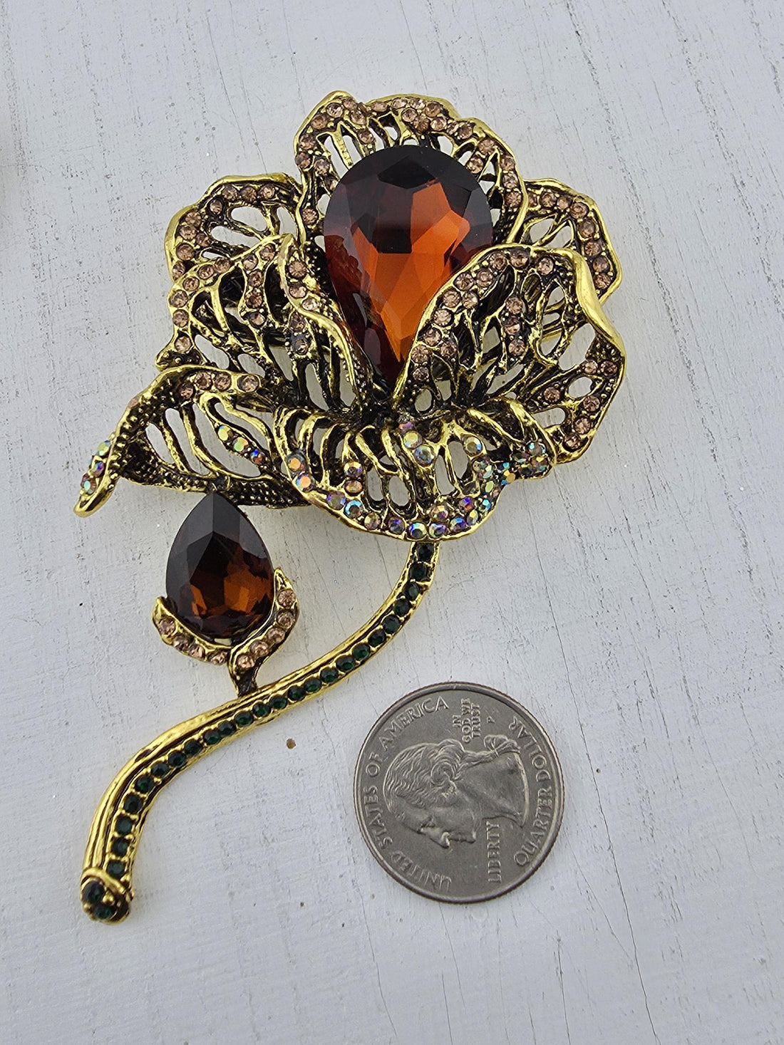 A decorative brooch with a floral design and large, dark-colored gemstones.