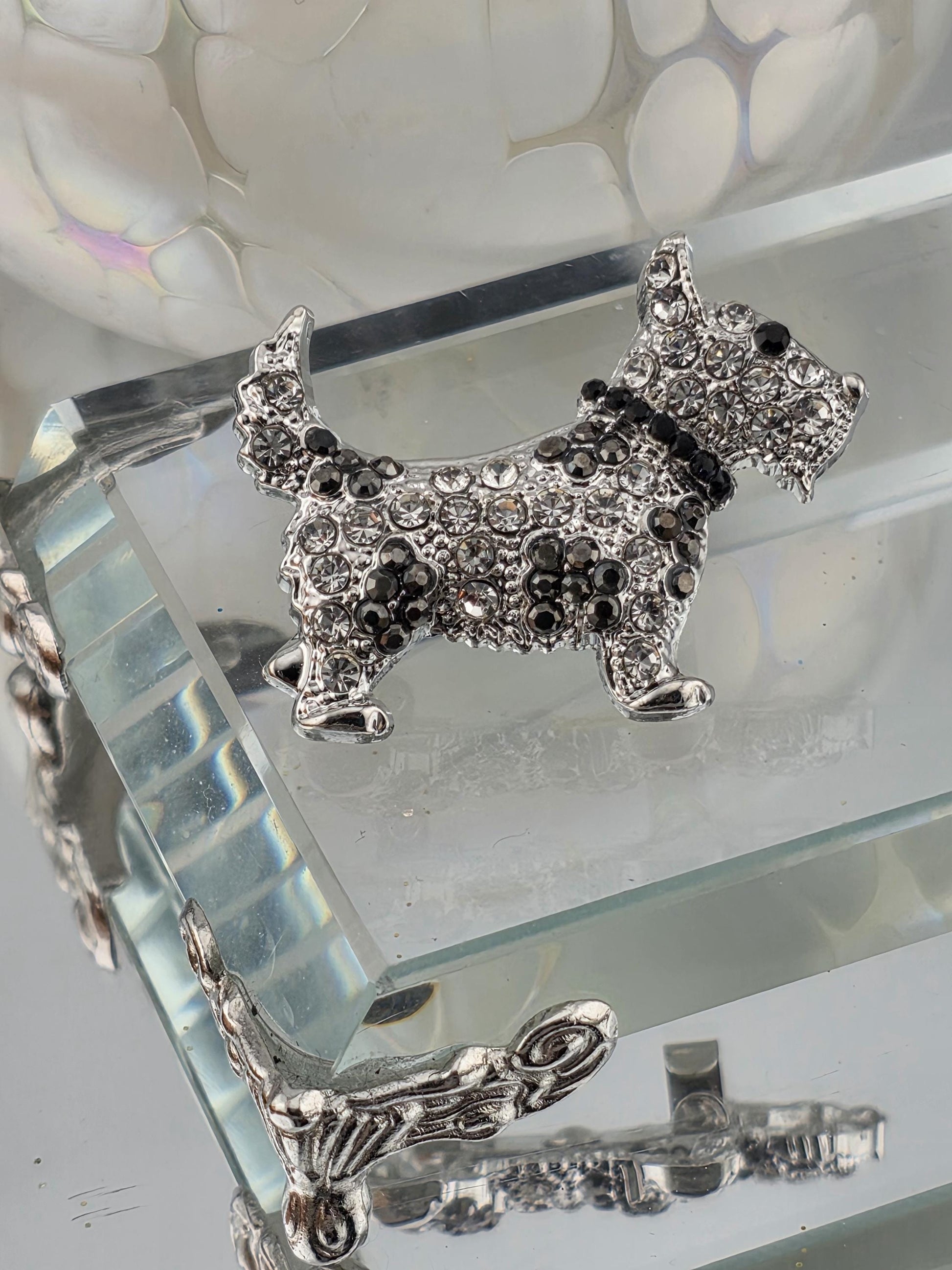 a silver-colored decorative piece with a crystal or gemstone design, placed on a glass surface.