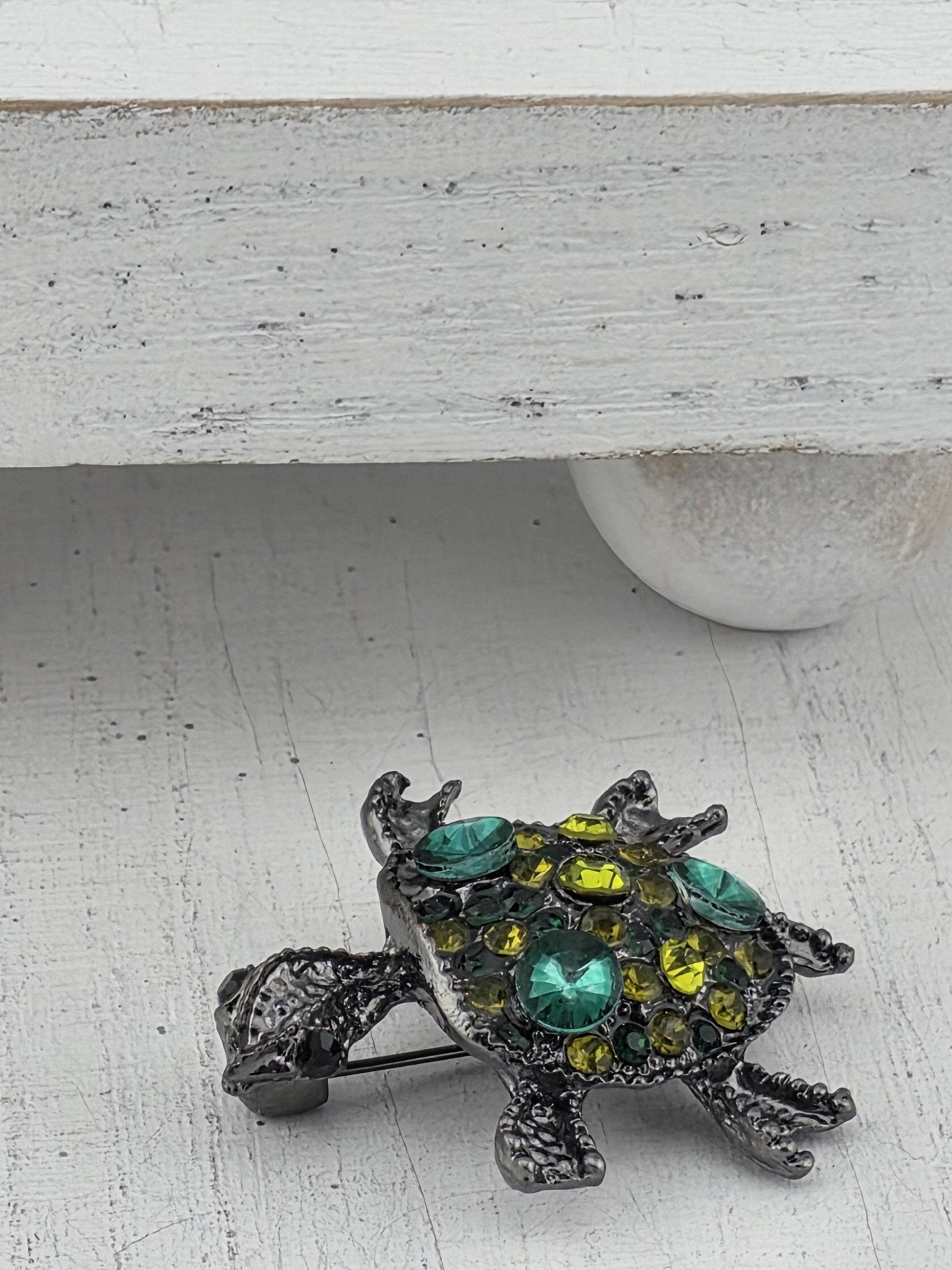 A decorative metal pin with a colorful, intricate design is displayed on a white wall.