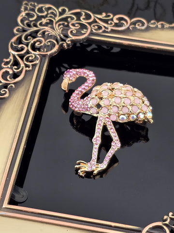 a decorative frame with a pink flamingo brooch on it.