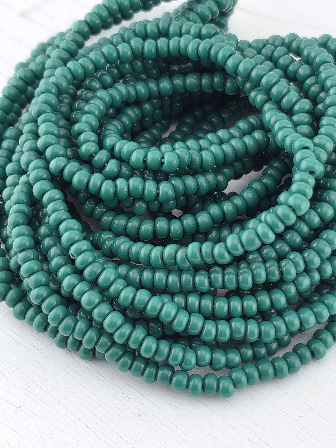 A large pile of green beads arranged in a spiral pattern on a white surface.