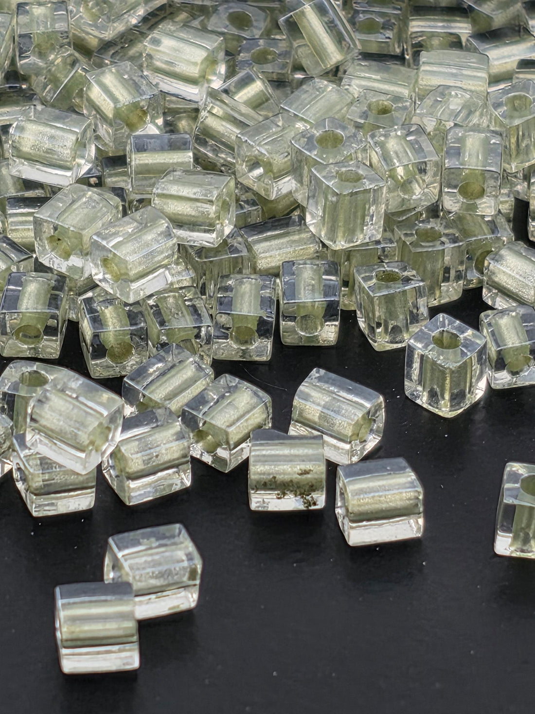 a collection of clear, transparent glass beads scattered on a dark background.