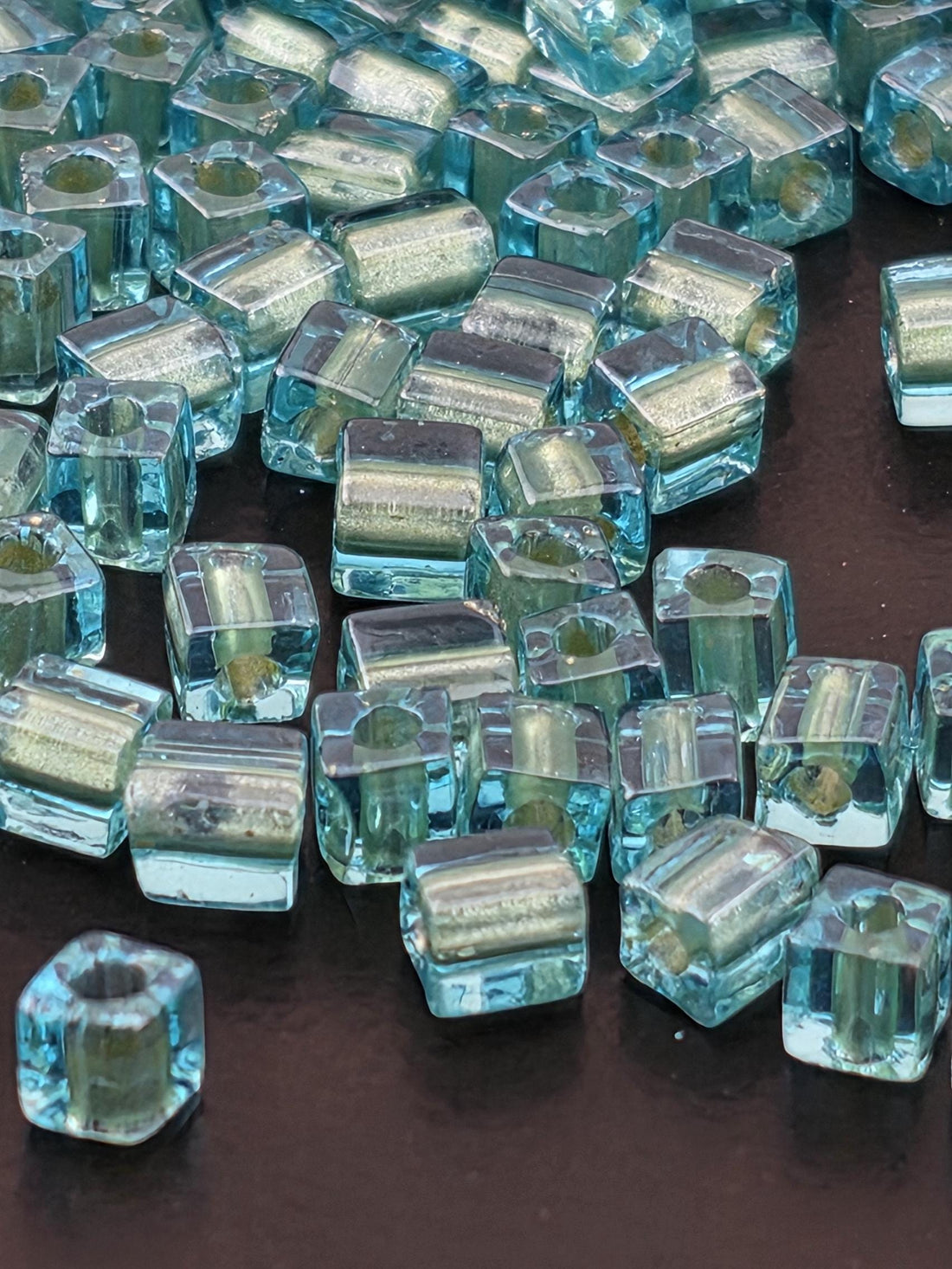 a close-up view of numerous small, clear glass beads scattered across a dark background.