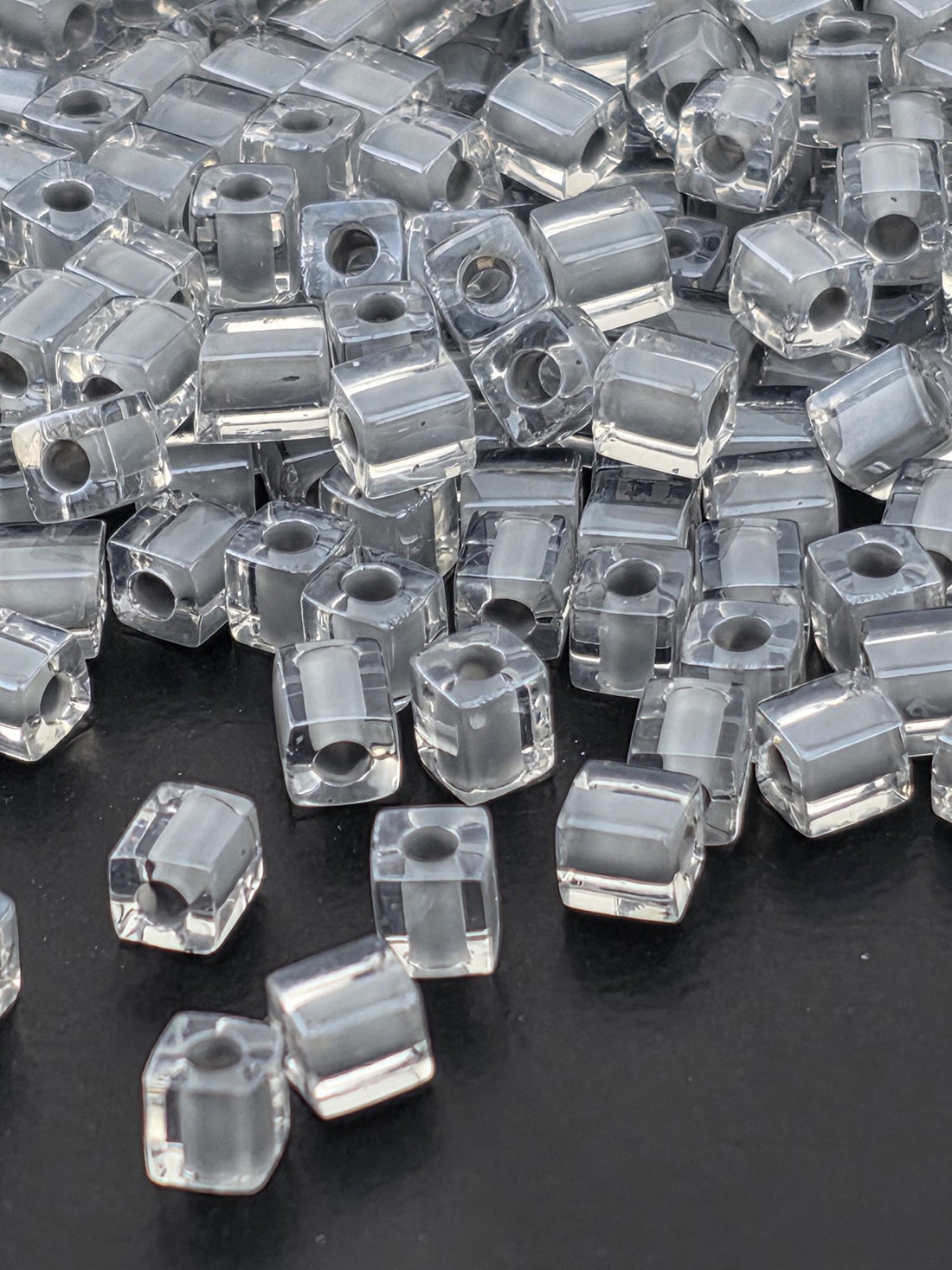 a close-up view of numerous clear glass beads scattered on a dark background.