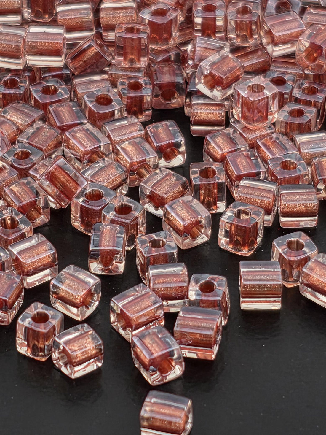 a close-up view of numerous clear glass beads scattered on a dark surface.