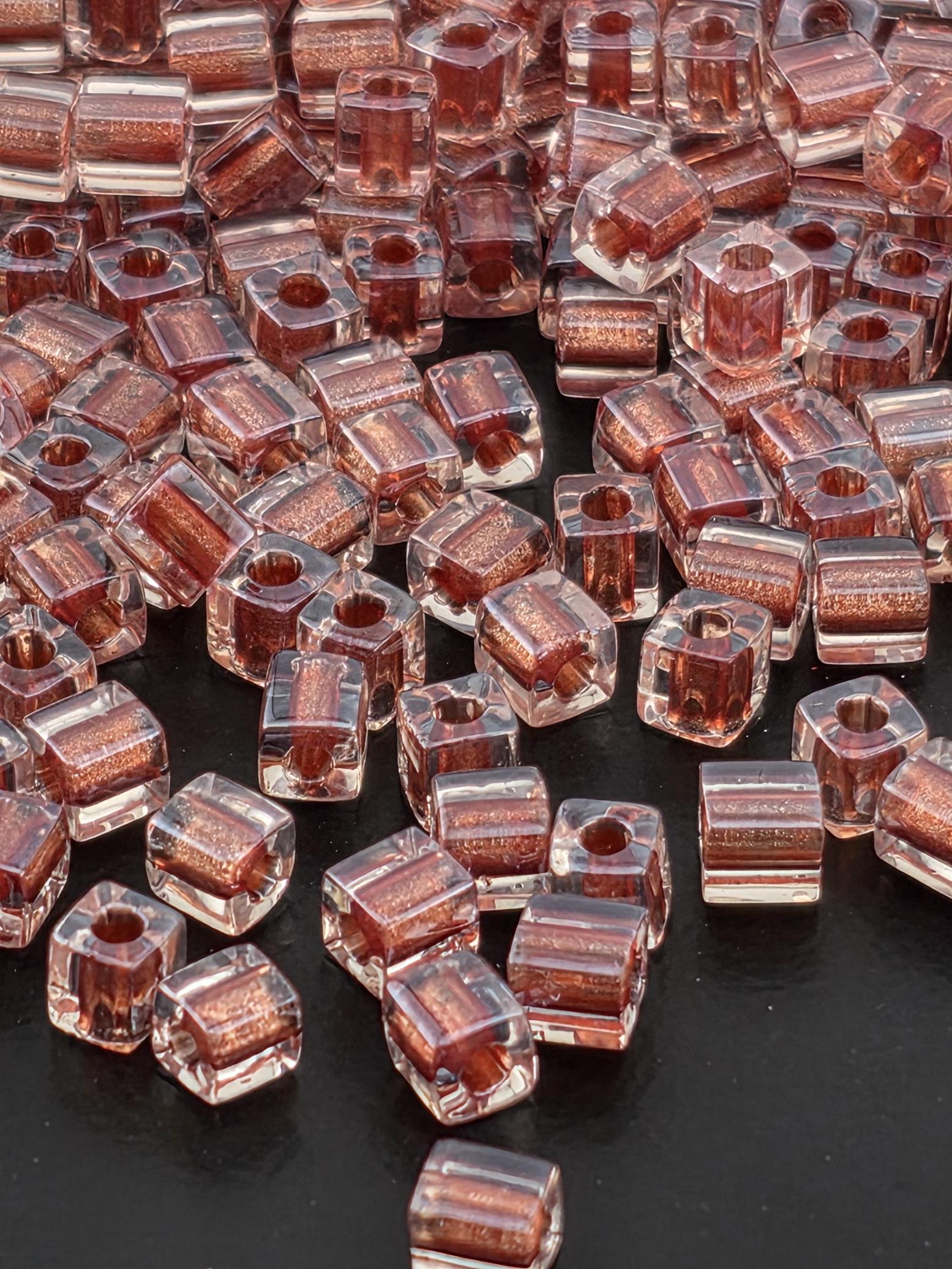 a close-up view of numerous clear glass beads scattered on a dark surface.