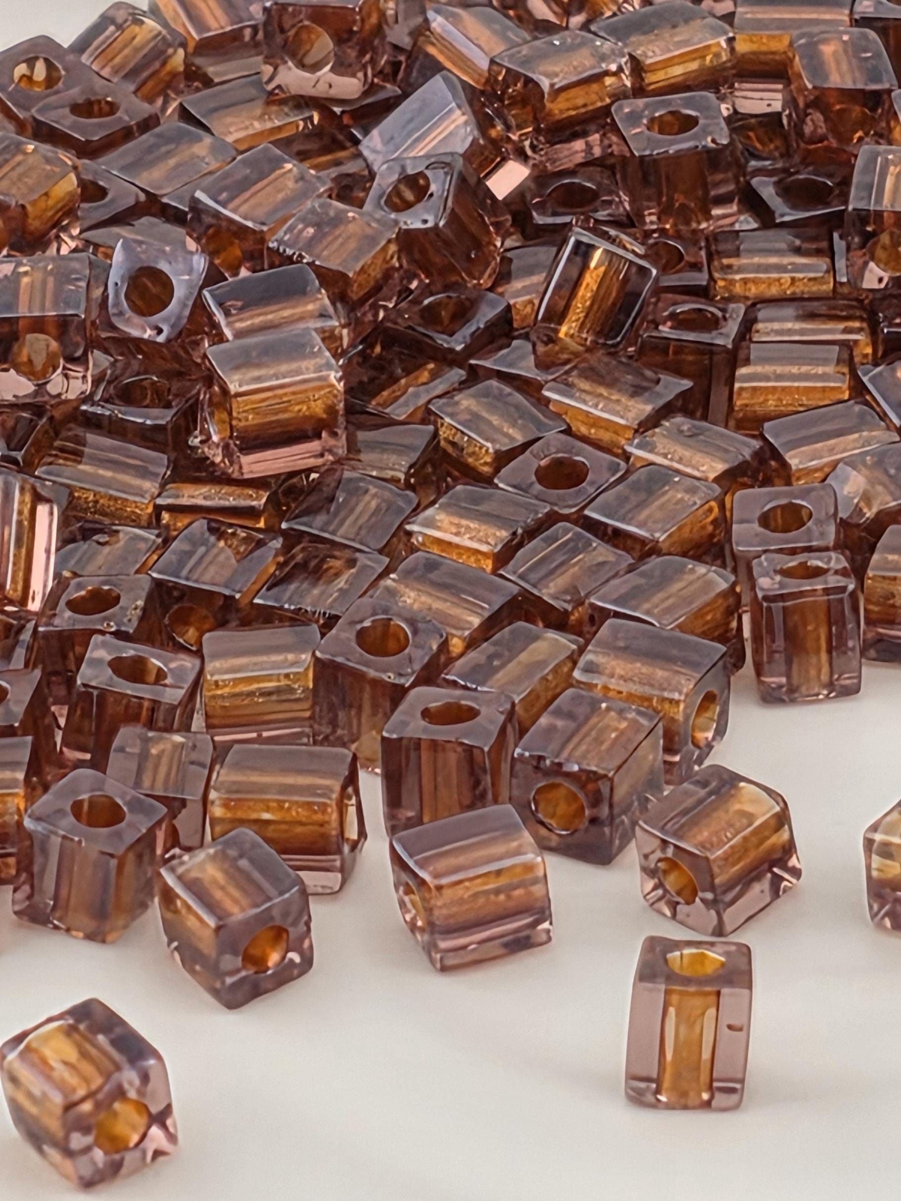 a close-up view of numerous small, clear beads in various shades of brown and orange, scattered across a surface.