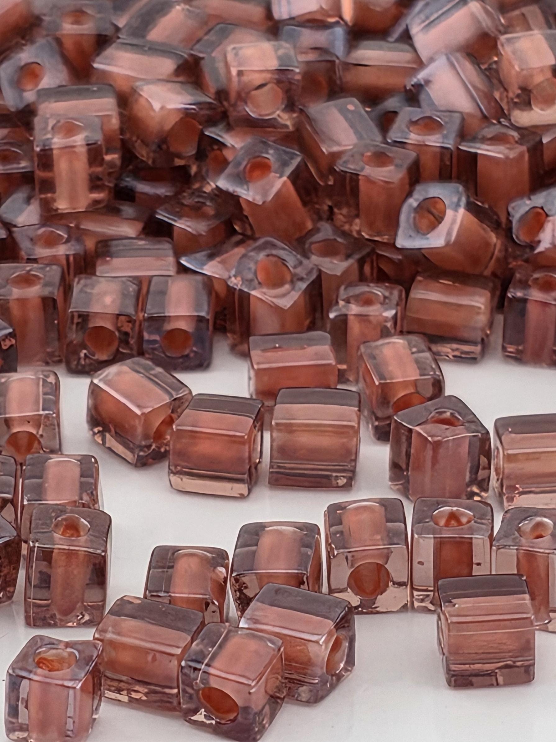 numerous small, clear glass beads in various shades of brown, scattered across a surface.