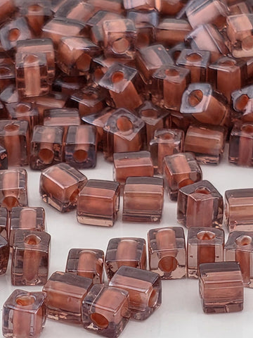 numerous small, clear glass beads in various shades of brown, scattered across a surface.