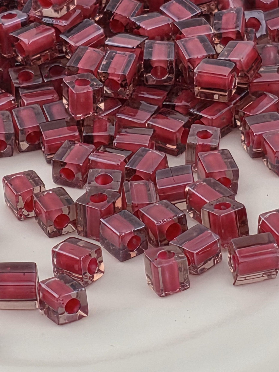 a close-up view of numerous small, clear, and red-colored glass beads or stones arranged in a pattern.