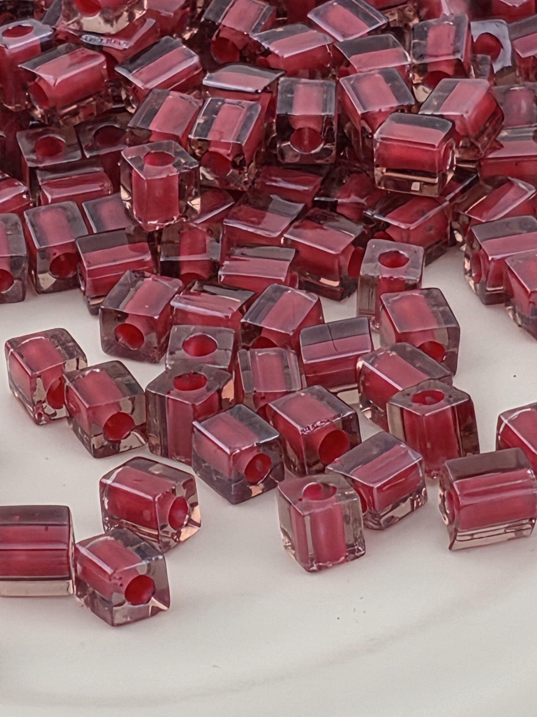 a close-up view of numerous small, clear, and red-colored glass beads or stones arranged in a pattern.