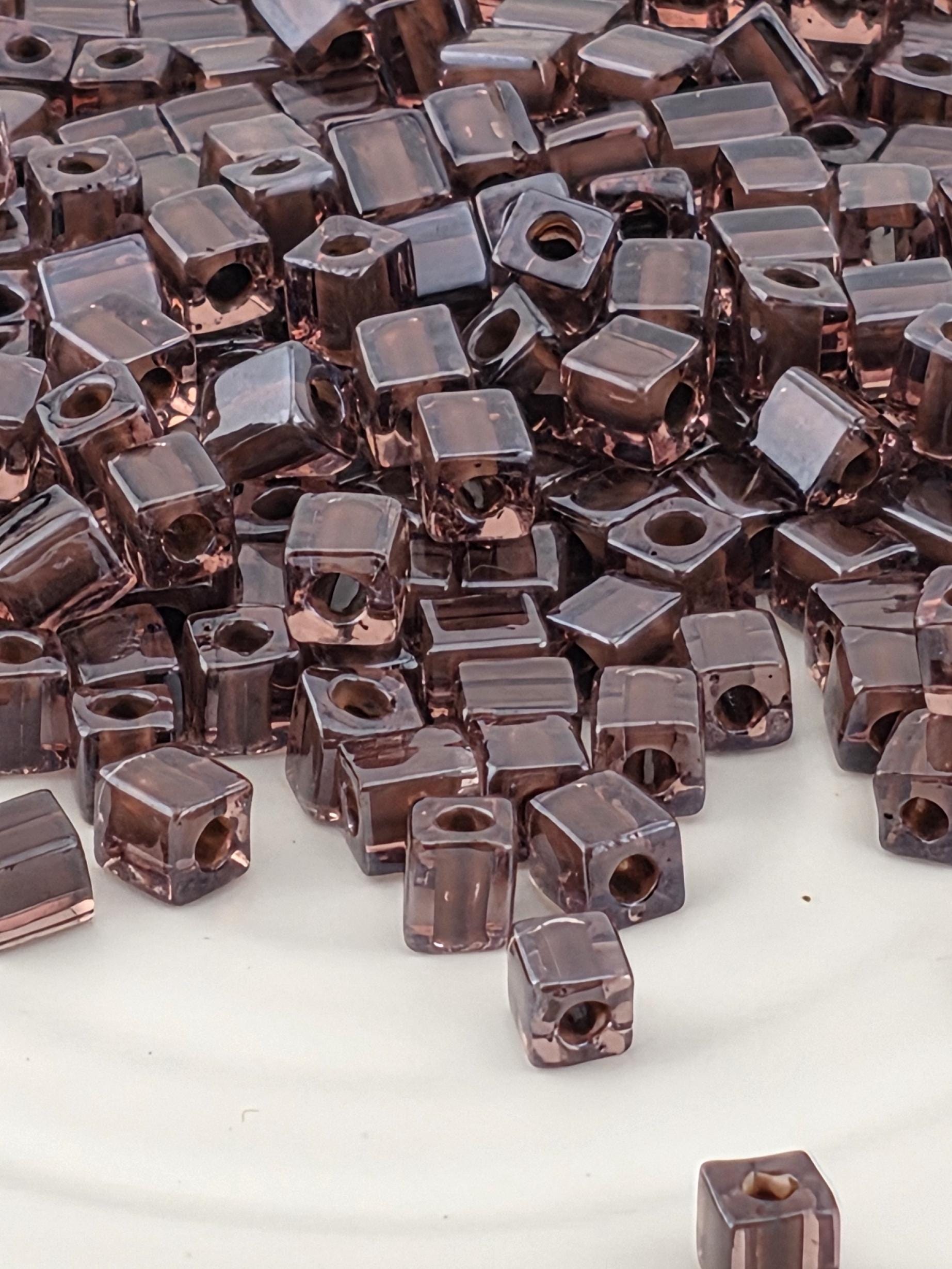 a close-up view of numerous small, square-shaped objects with a dark brown color, scattered across a surface.