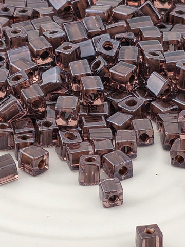 a close-up view of numerous small, square-shaped objects with a dark brown color, scattered across a surface.