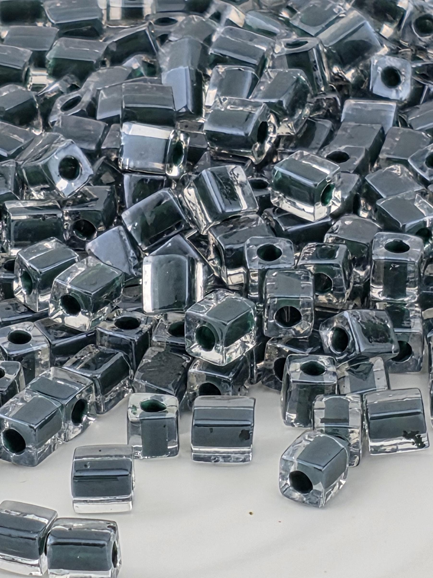 The image is a close-up of numerous small, metallic beads or nuts arranged in a visually striking manner.