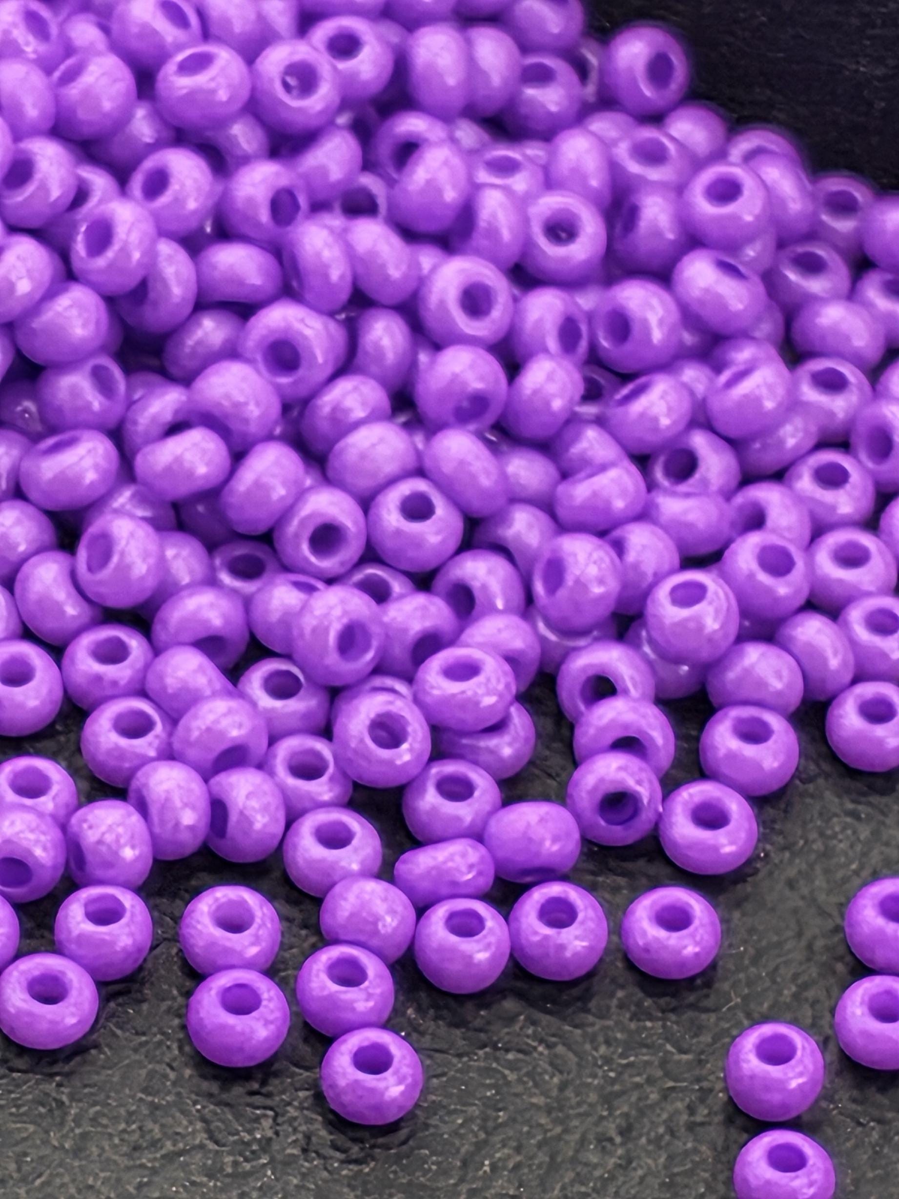 A pile of purple beads scattered on a dark surface.