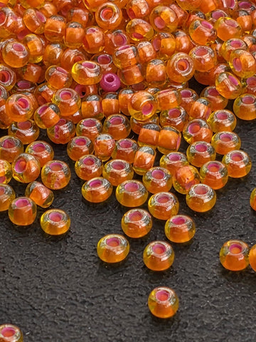 a collection of small, round, orange glass beads scattered on a dark surface.