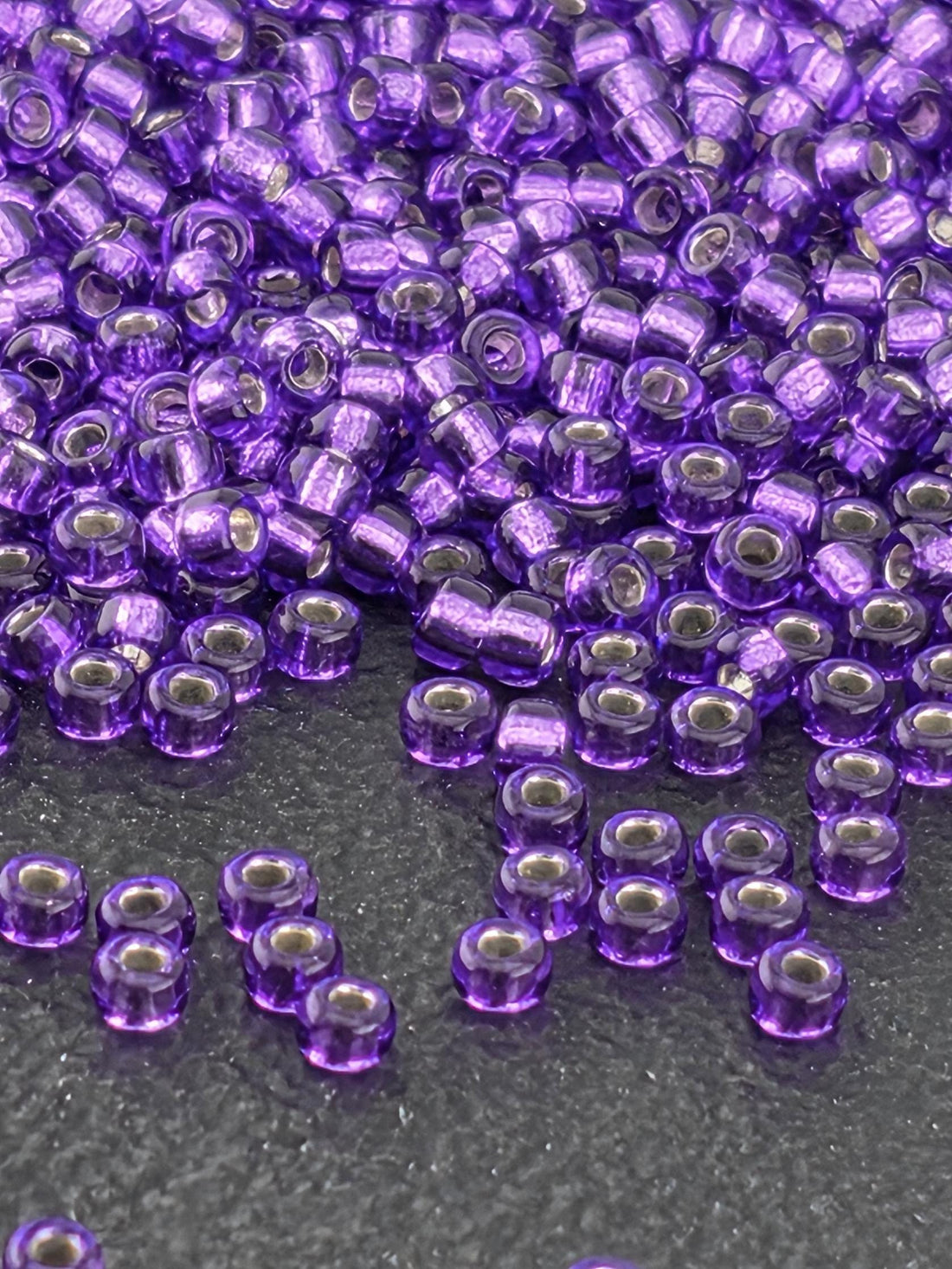 a close-up view of numerous purple beads scattered on a dark surface.