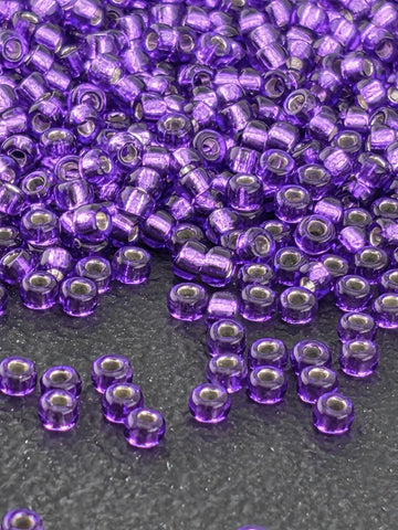 a close-up view of numerous purple beads scattered on a dark surface.