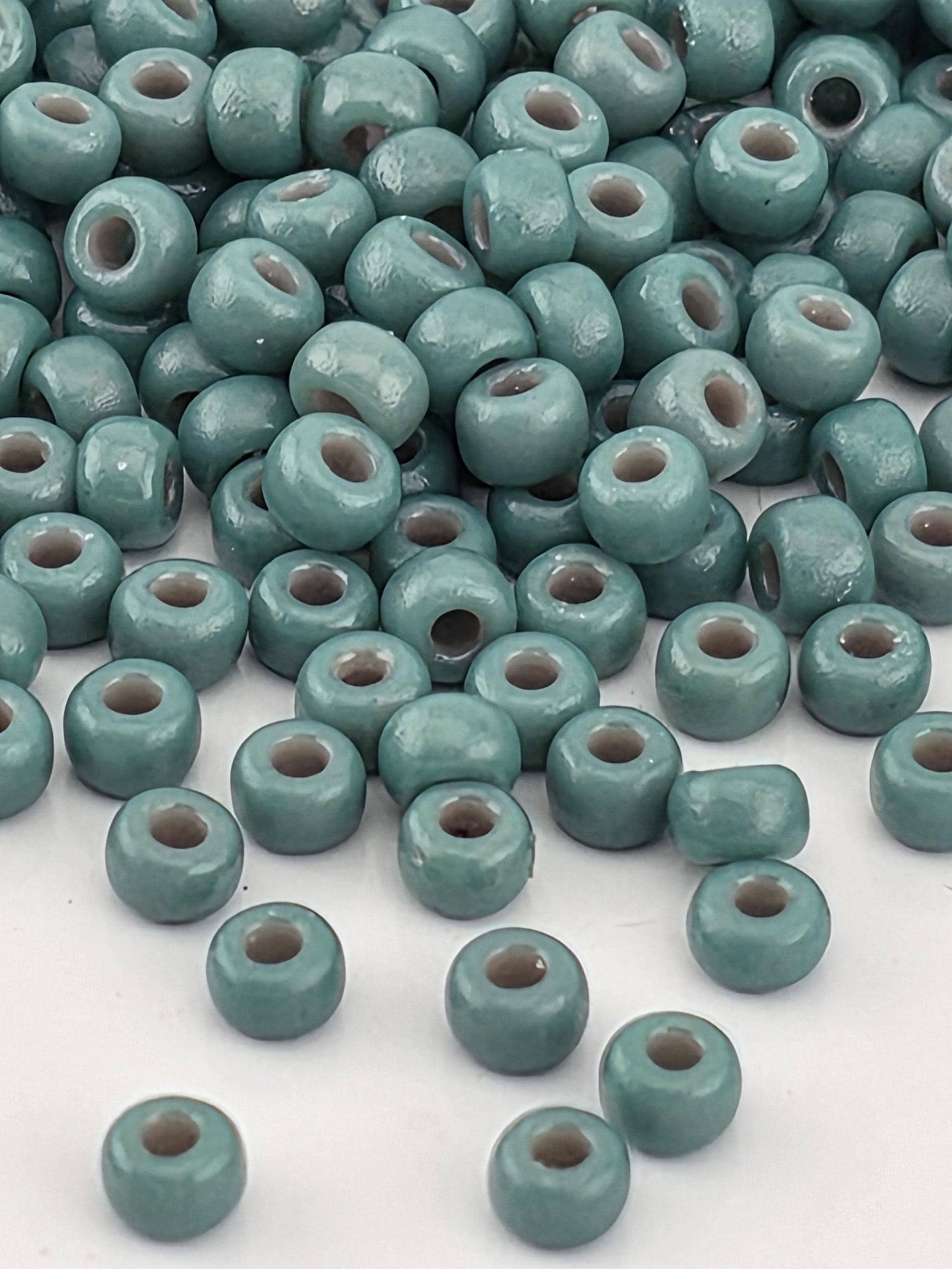 a collection of small, round beads in various shades of blue and green, scattered across a white surface.