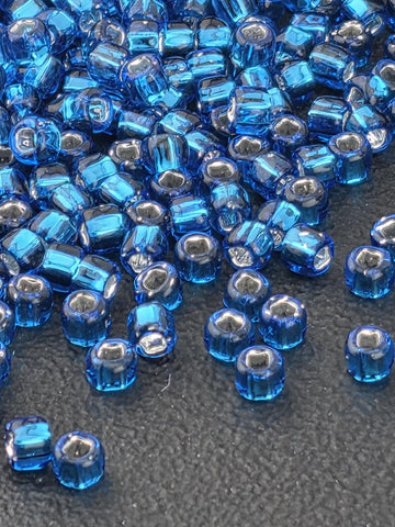 a close-up view of numerous blue and silver beads scattered on a textured surface.
