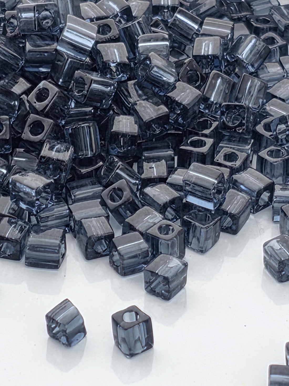 a large pile of small, square-shaped objects, likely made of metal or glass, scattered across a white surface.