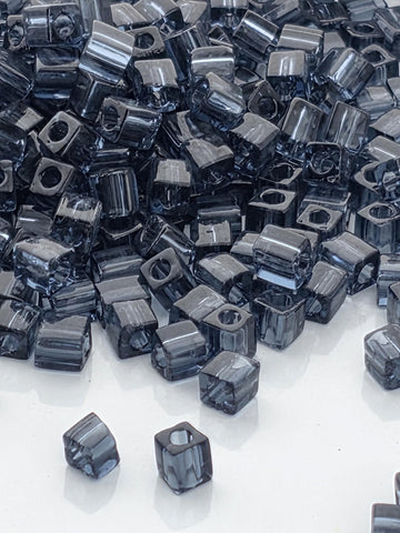 a large pile of small, square-shaped objects, likely made of metal or glass, scattered across a white surface.