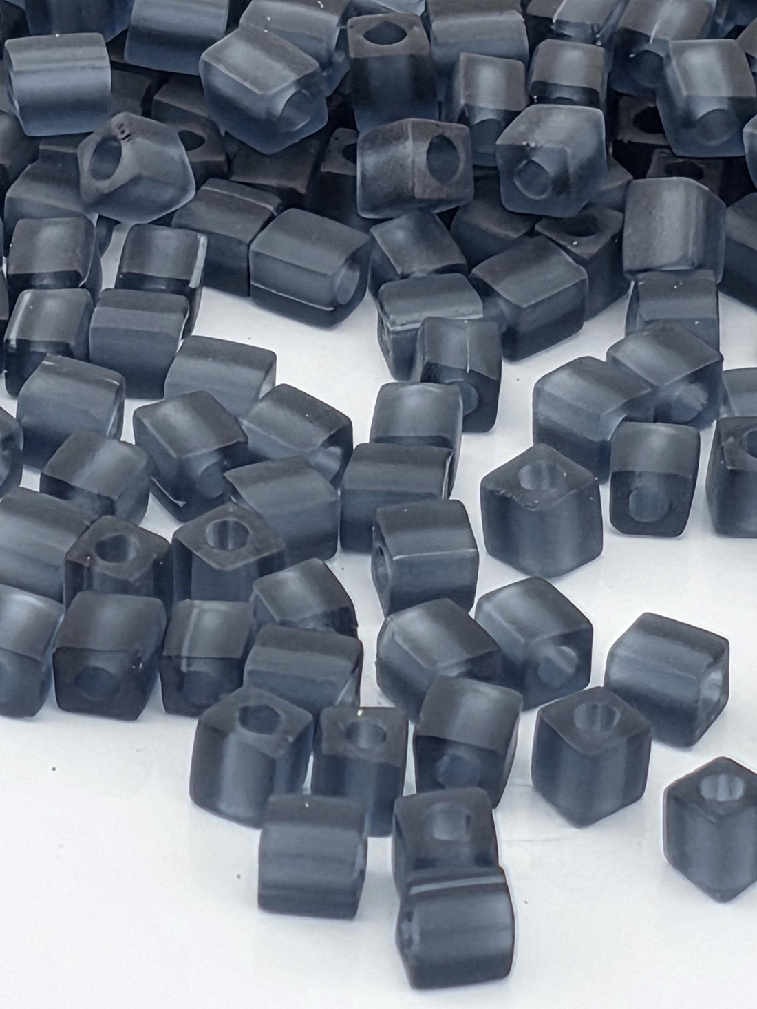 numerous small, square-shaped objects that appear to be made of a dark material, possibly metal or plastic. The objects are scattered across a surface, creating a visually interesting and somewhat chaotic arrangement.