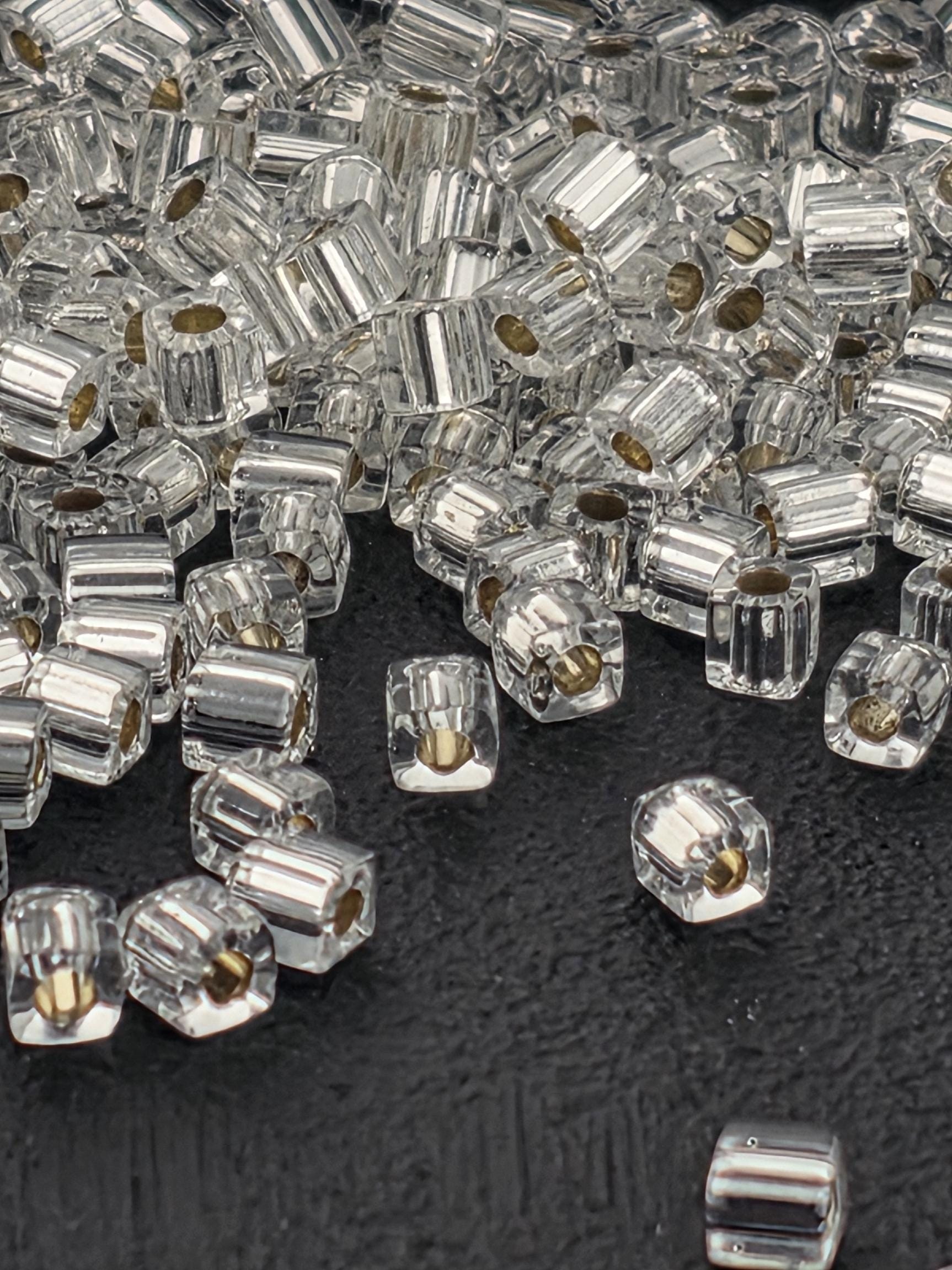 a close-up view of numerous clear glass beads scattered on a black surface.