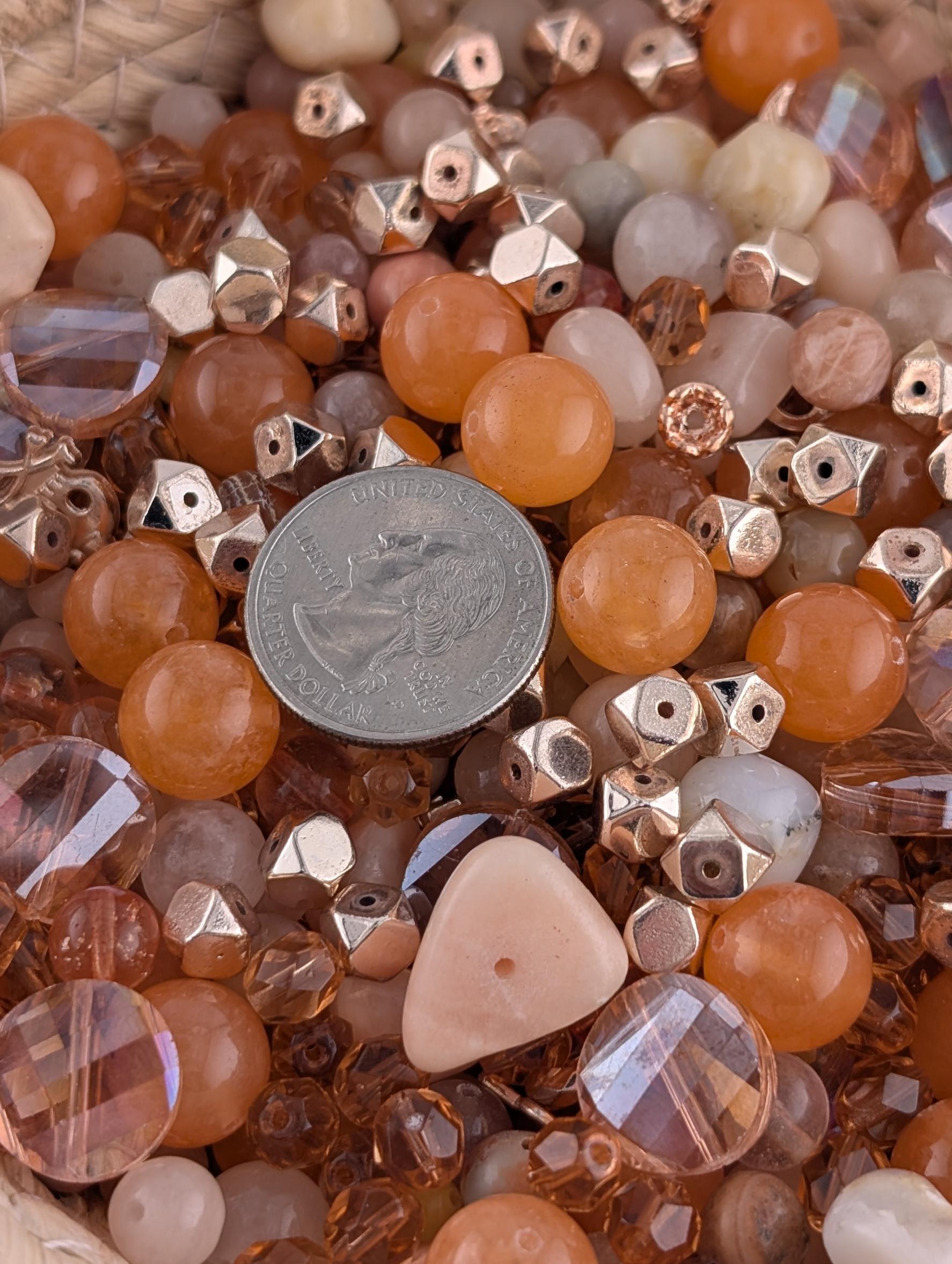 a close-up view of a collection of various beads and coins, including clear and colored glass beads, as well as a silver coin.