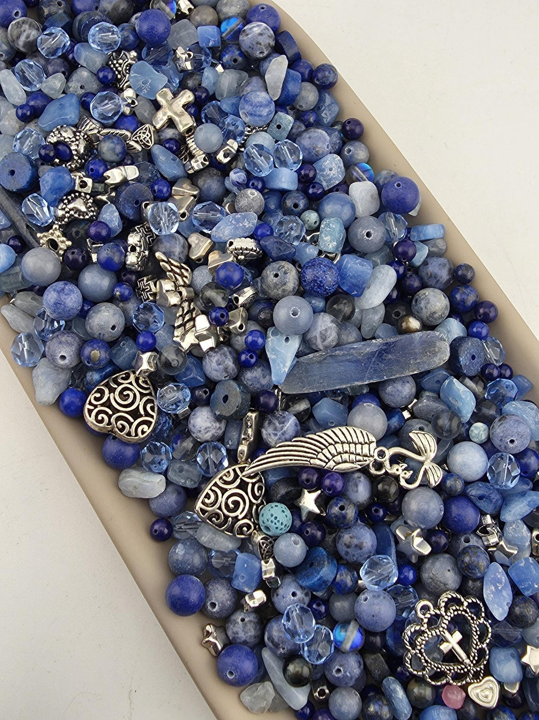 A collection of various blue beads, charms, and other decorative items arranged in a visually appealing manner.