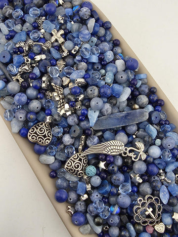 A collection of various blue beads, charms, and other decorative items arranged in a visually appealing manner.