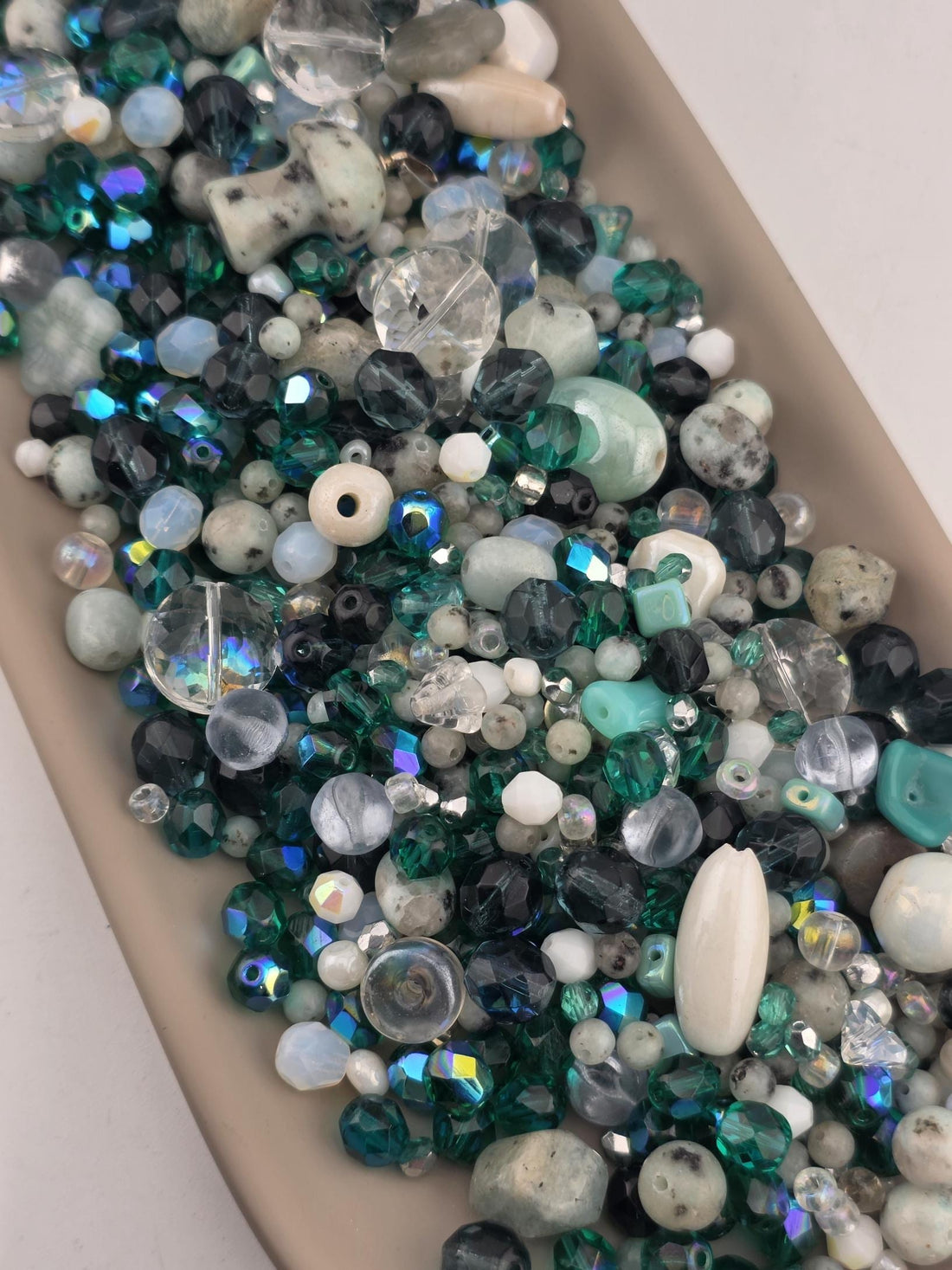 A collection of various colored beads, including clear, white, blue, green, and black beads, arranged in a visually appealing manner.