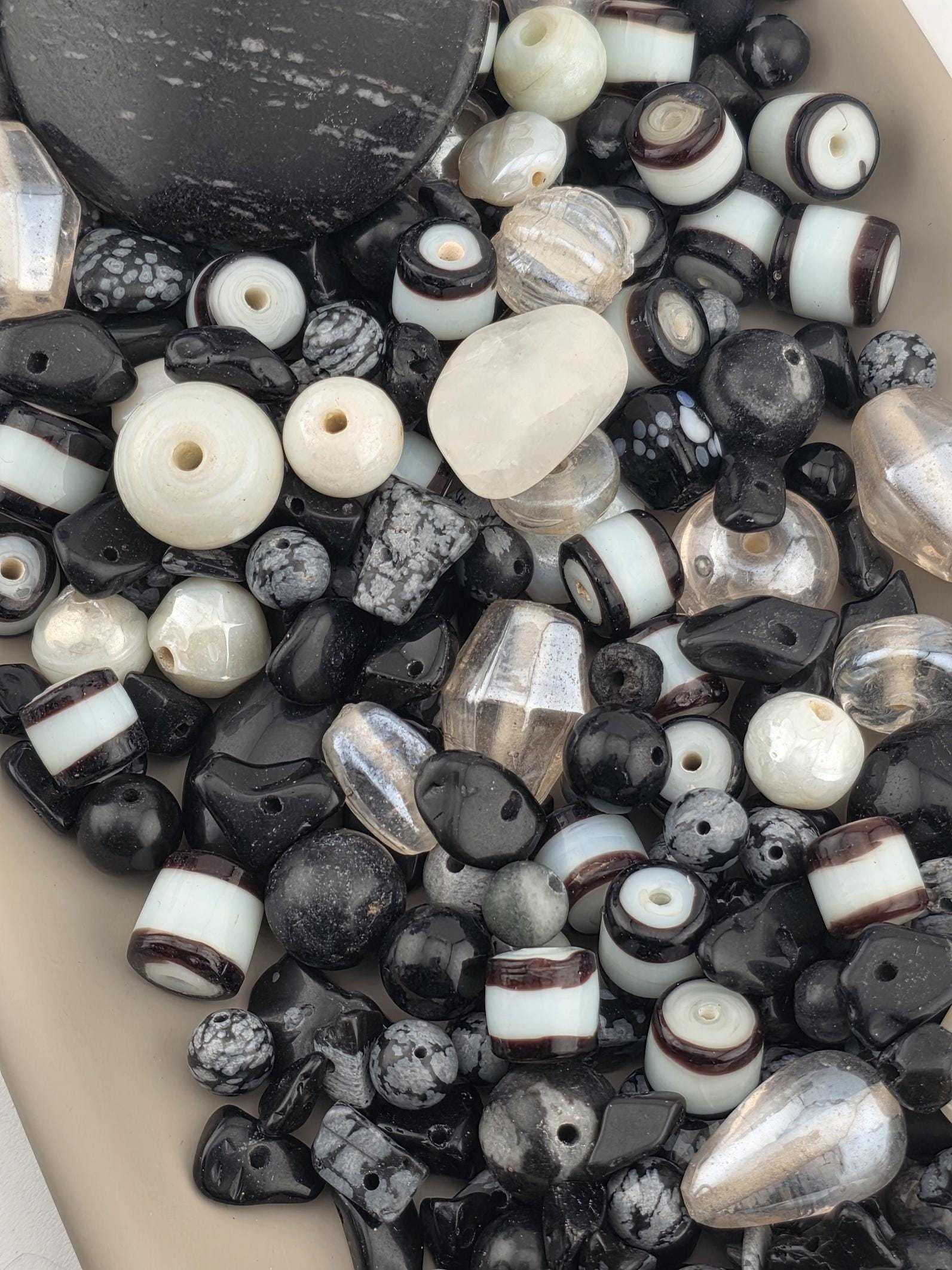 a variety of beads in different shapes, sizes, and colors, including black, white, and silver beads.