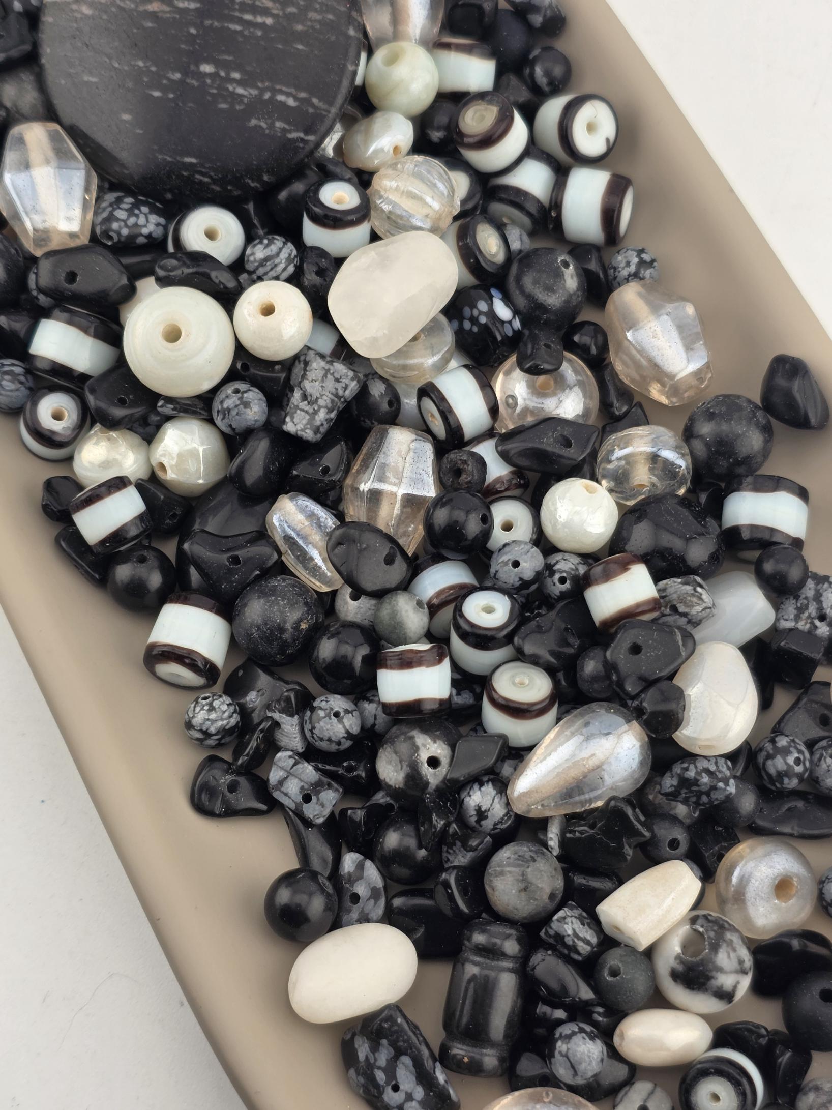 a collection of various beads and beads in different shapes and sizes, including clear and black beads, scattered on a surface.