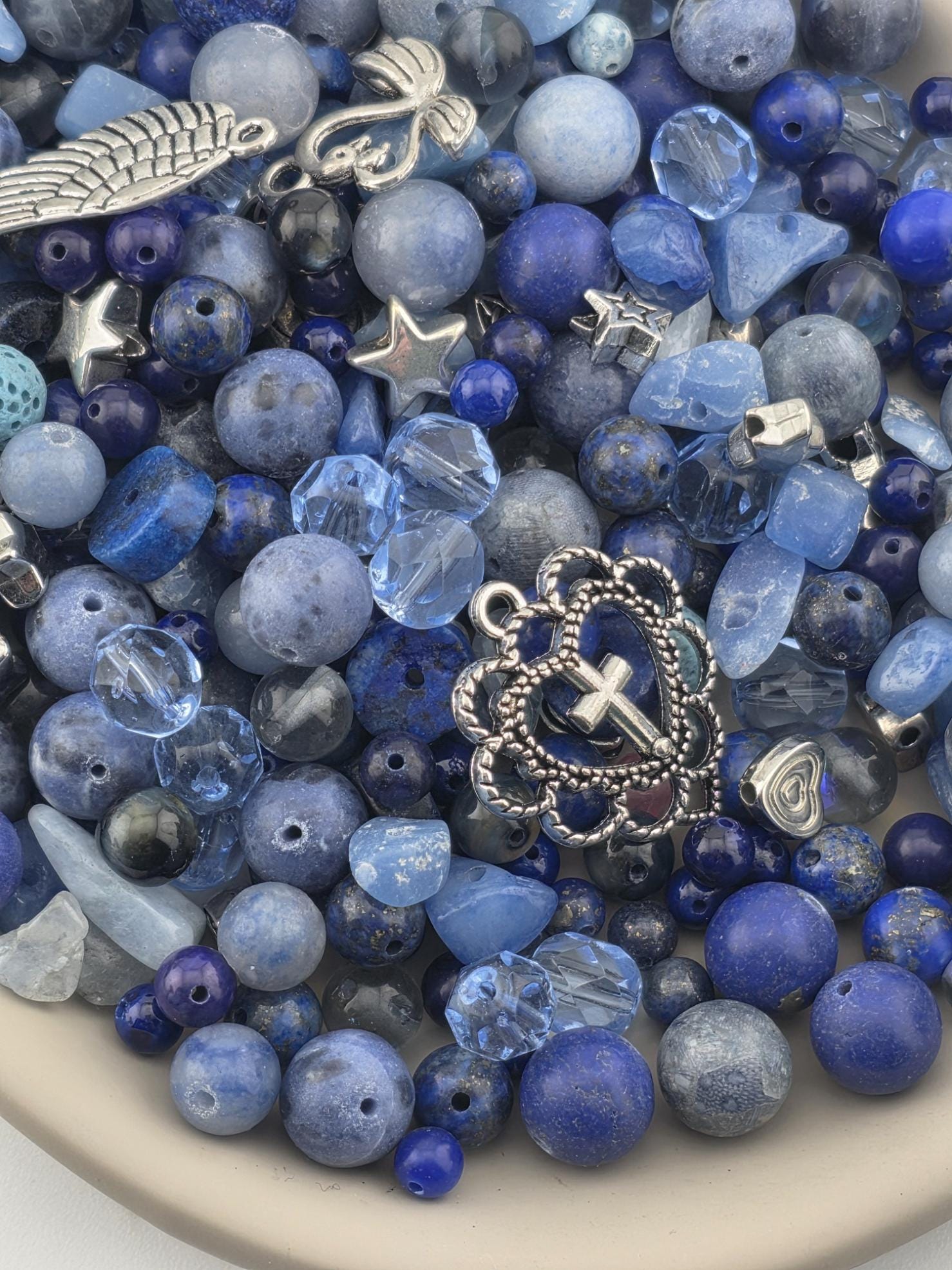 A bowl filled with various blue beads, charms, and other decorative items.