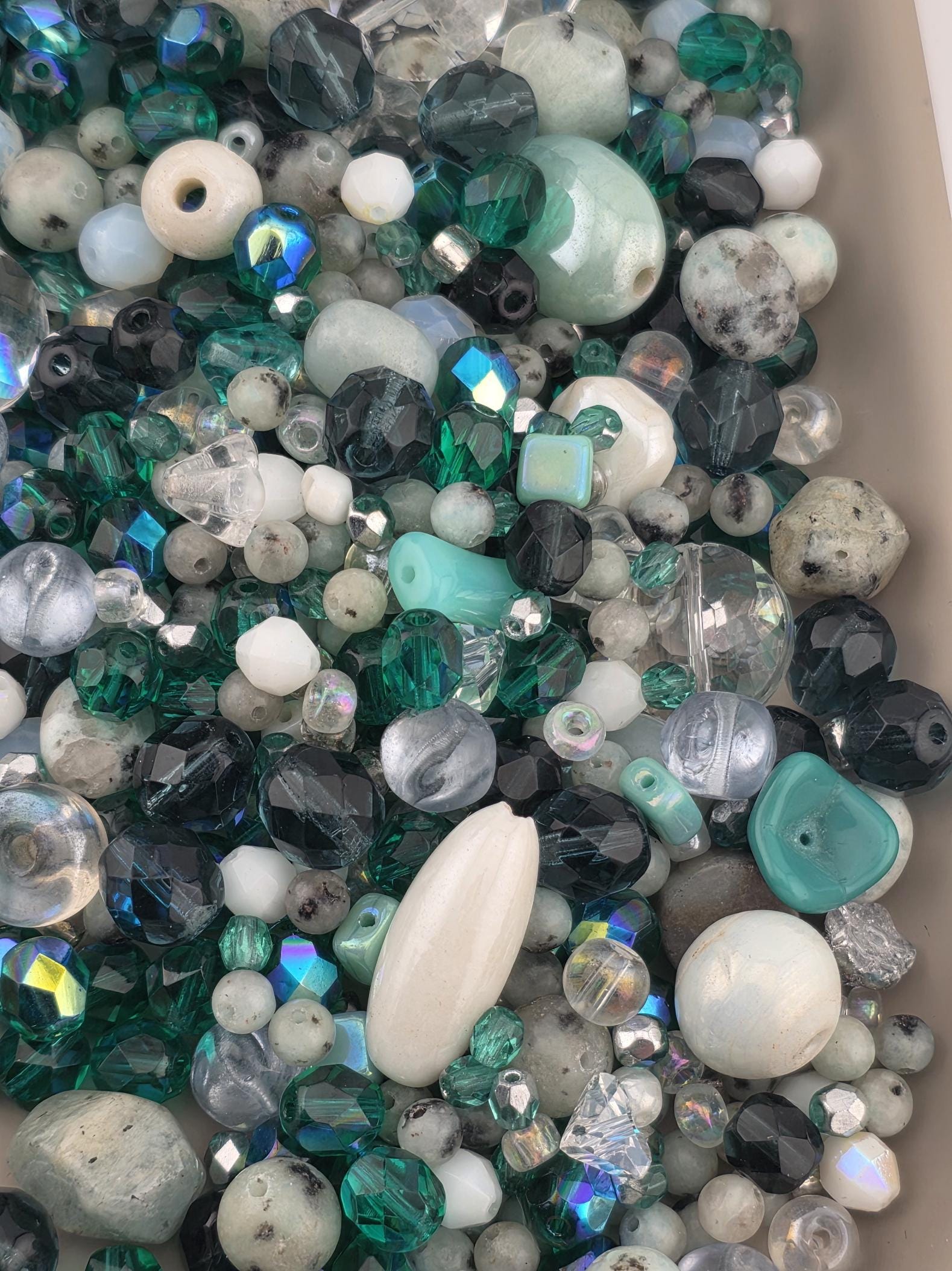 a variety of colorful beads and gemstones, including clear, white, and multicolored beads, as well as some larger stones.