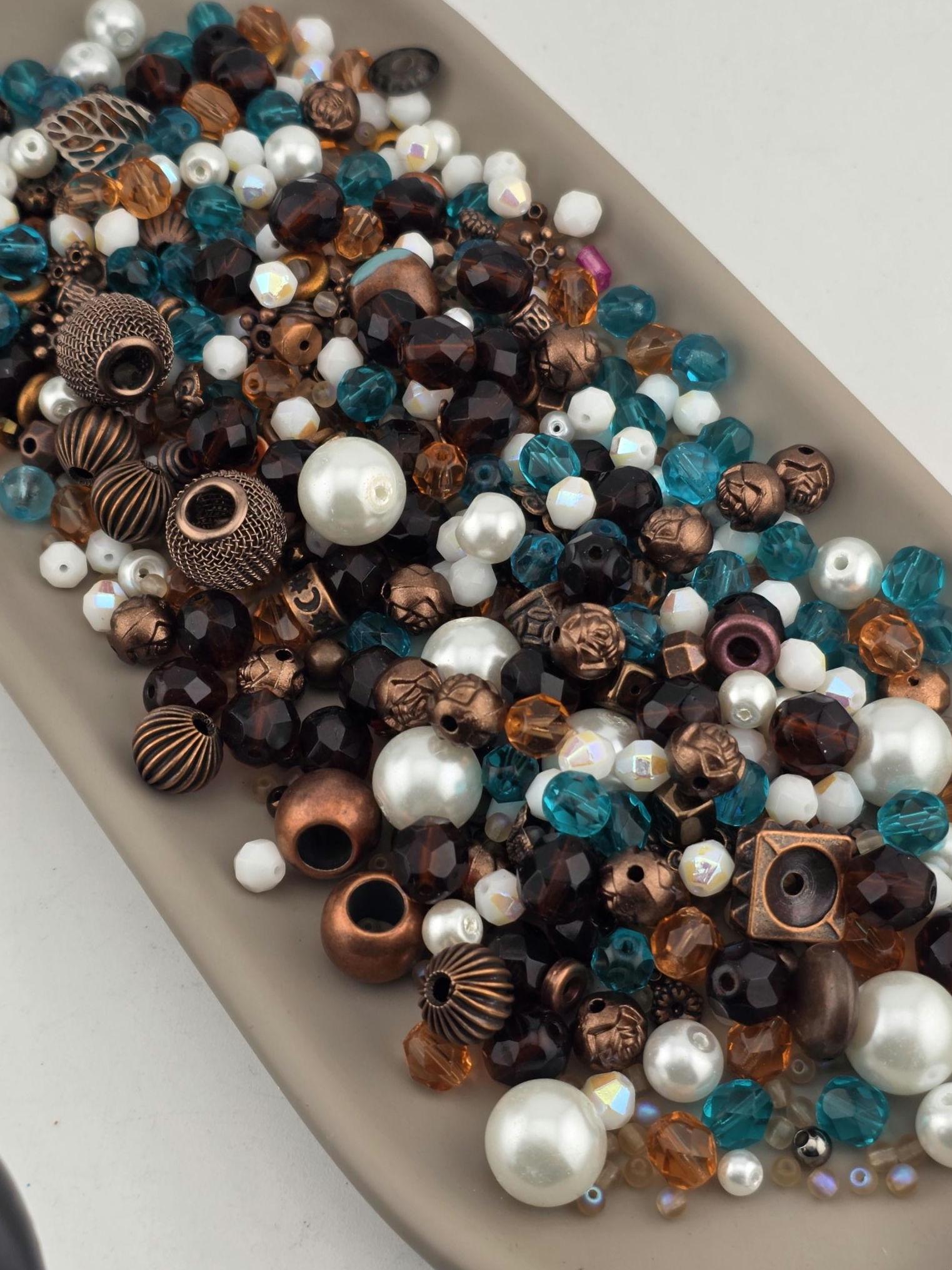 A collection of various beads, including white, blue, and brown, arranged on a white surface.