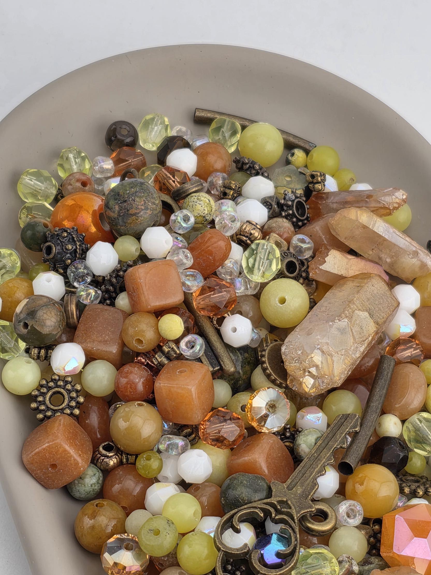 A plate filled with various beads, gemstones, and metal objects, including a key.