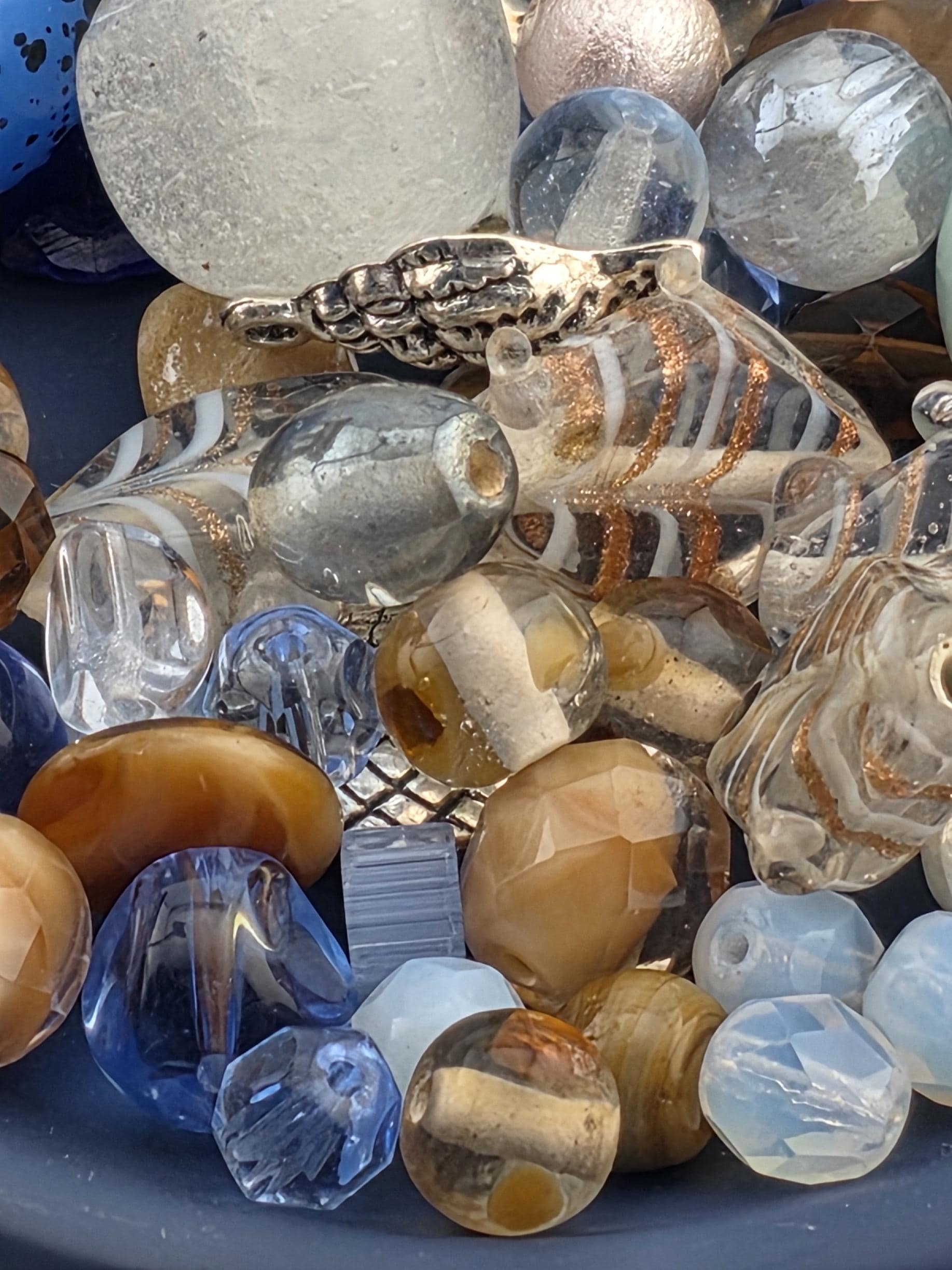 a variety of colorful glass beads and stones, including clear, blue, and brown glass beads, as well as some clear and brown glass stones.