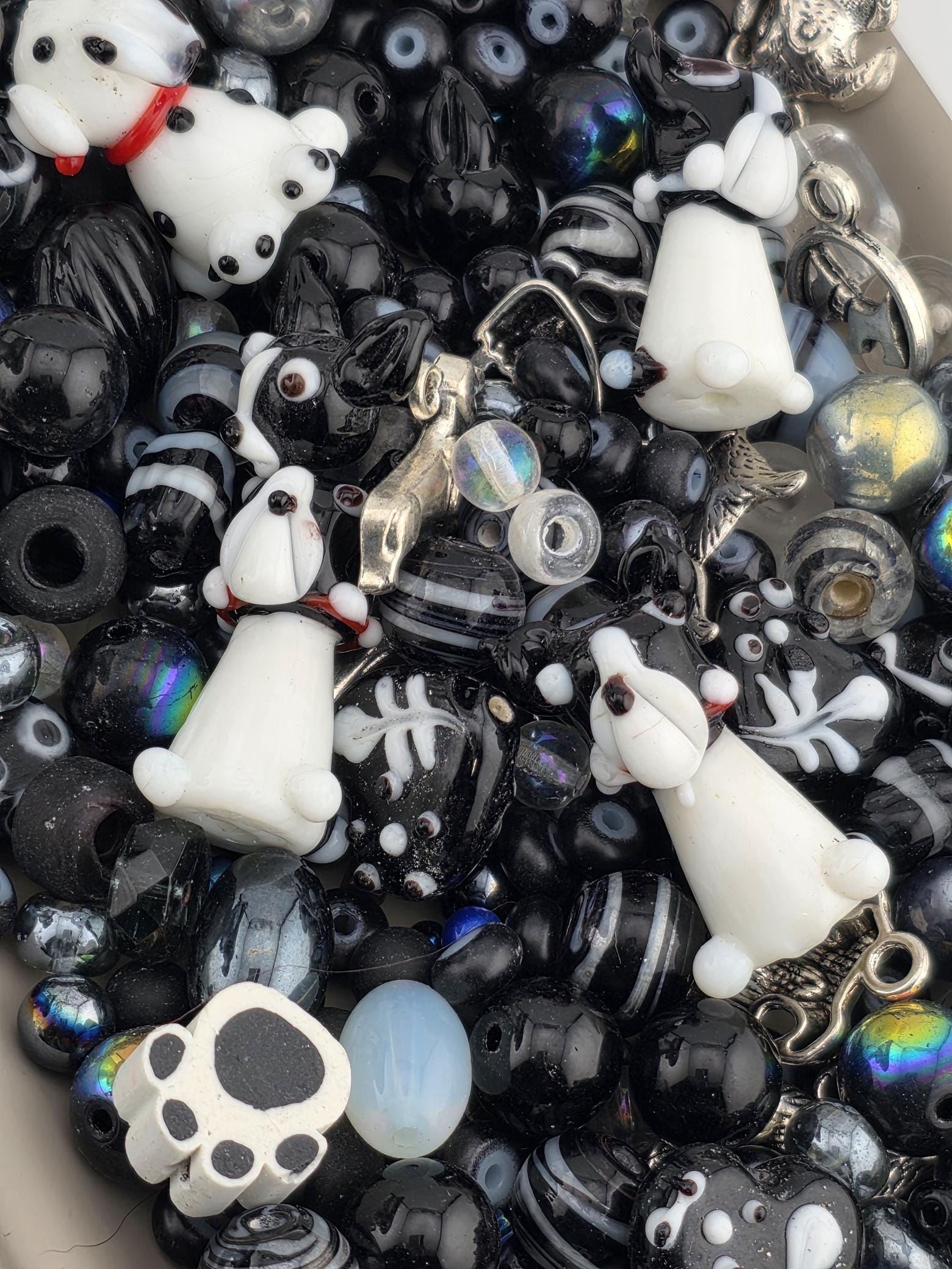 A collection of various beads, charms, and other small objects in shades of black and white, including beads, charms, and other decorative items.