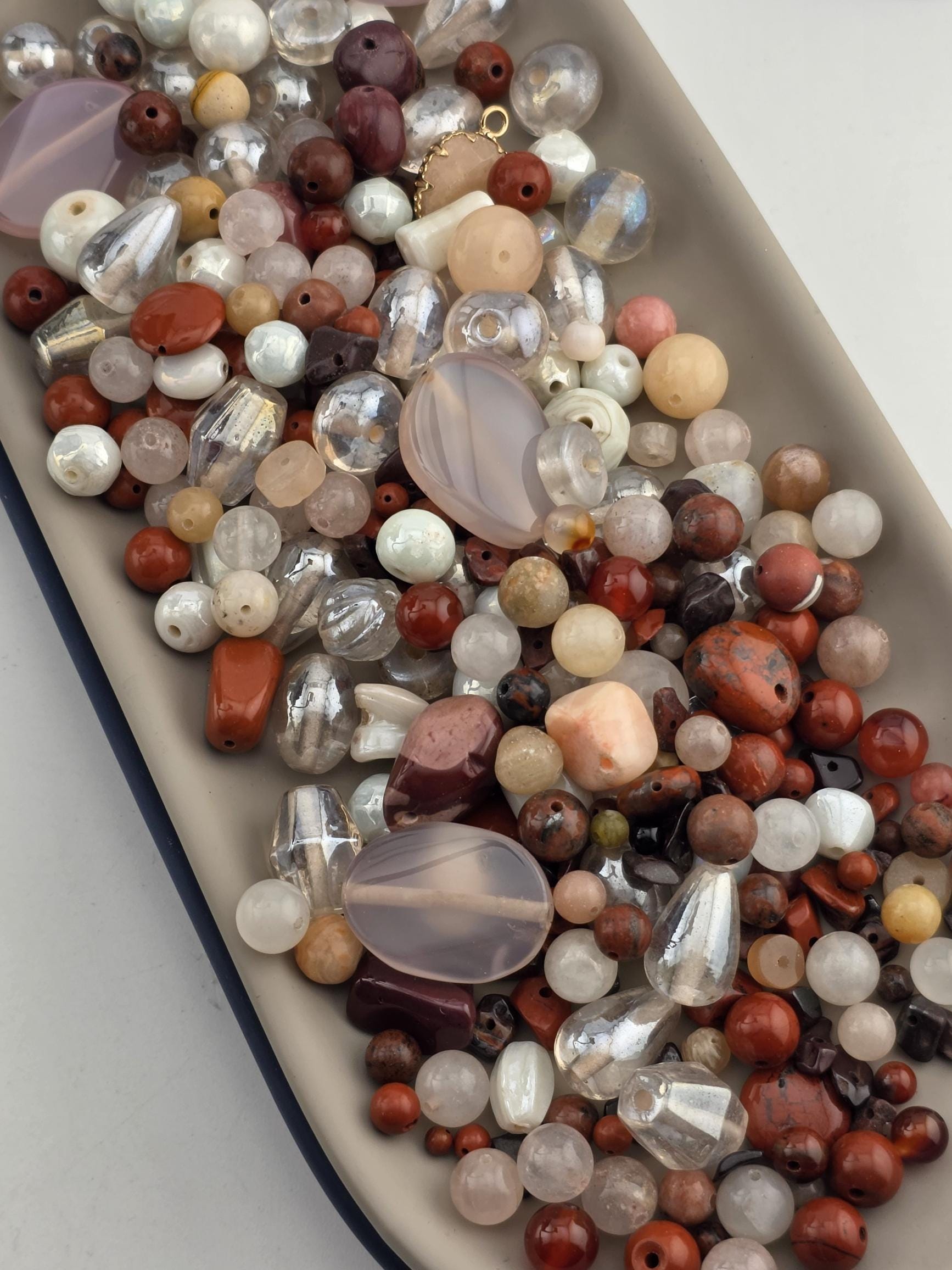 A tray filled with various colorful beads, including clear, clear, and multicolored beads, as well as some larger beads and beads with unique shapes and sizes.