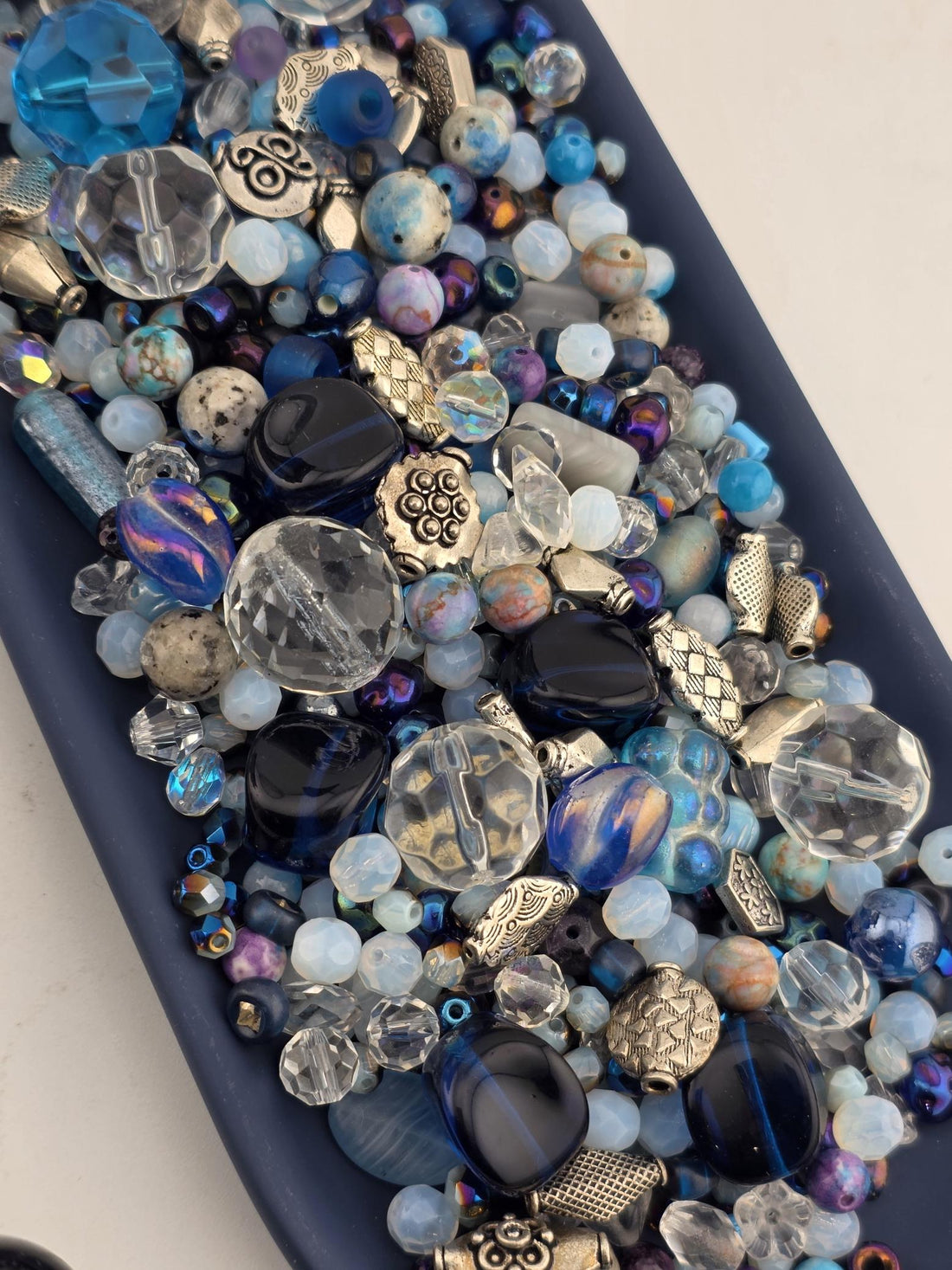 A collection of various colored glass beads and beads in different shapes and sizes, arranged on a dark surface.