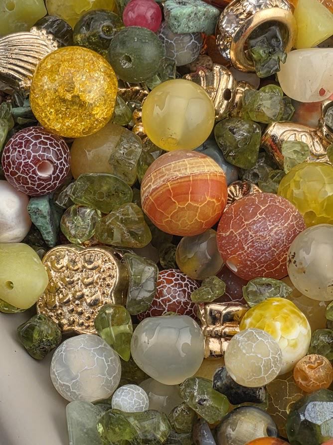 The image is a close-up of a collection of various colorful beads, gemstones, and other decorative objects.