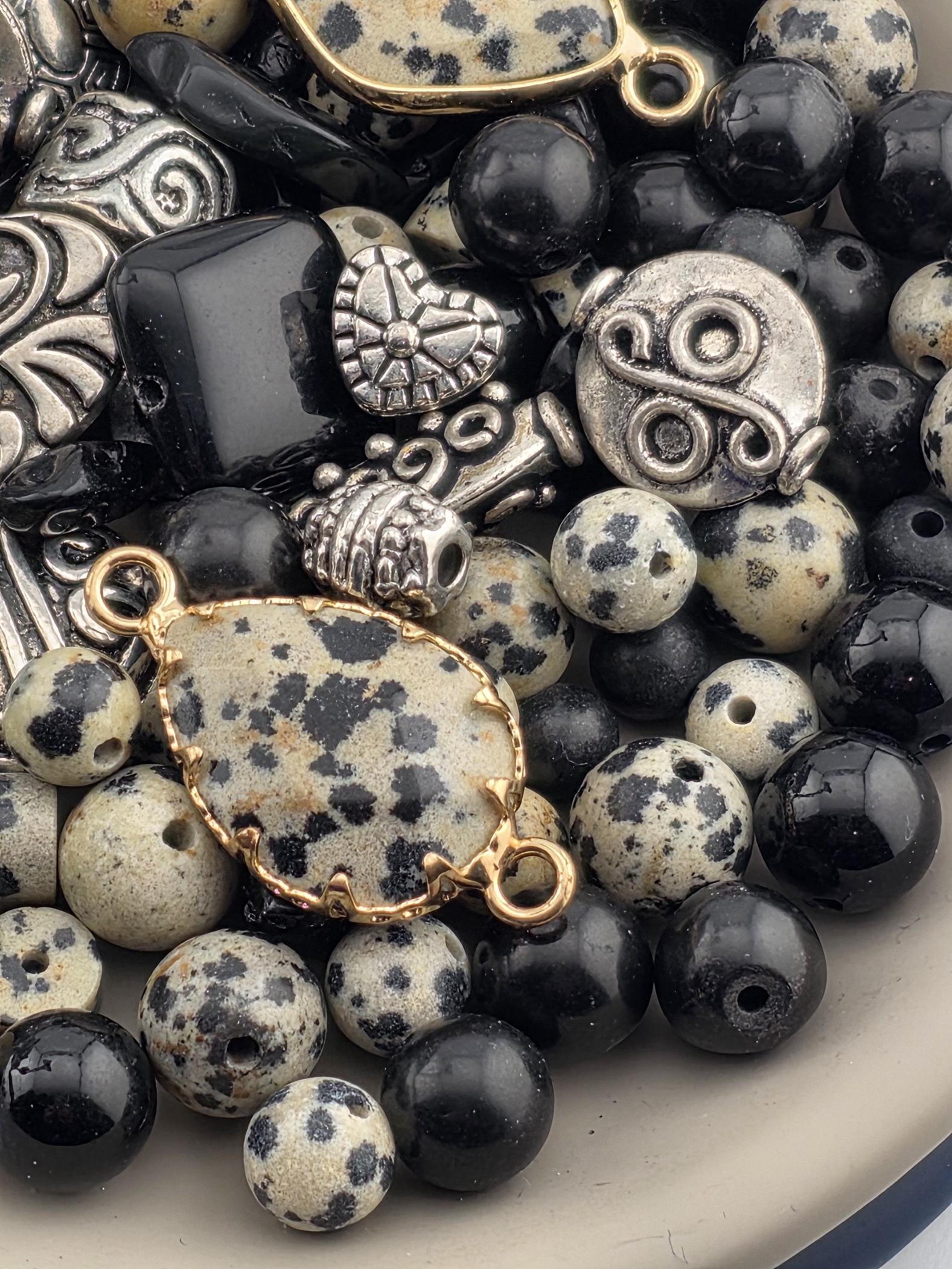 A close-up image of various beads, charms, and metal pieces in a bowl.