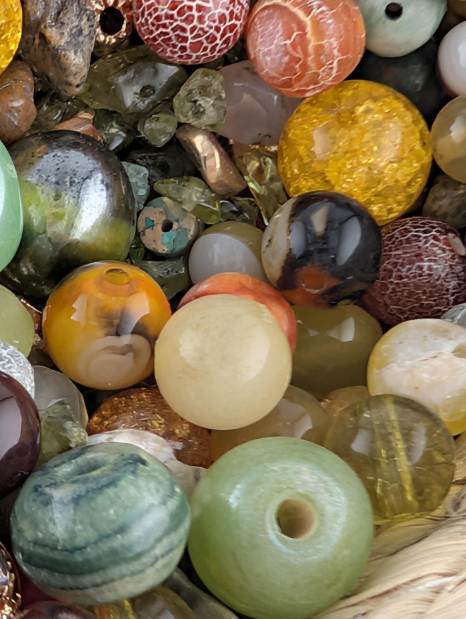 The image is a close-up of a collection of various colorful beads, stones, and glass objects, including glass beads, stones, and glass balls, arranged in a visually appealing manner.