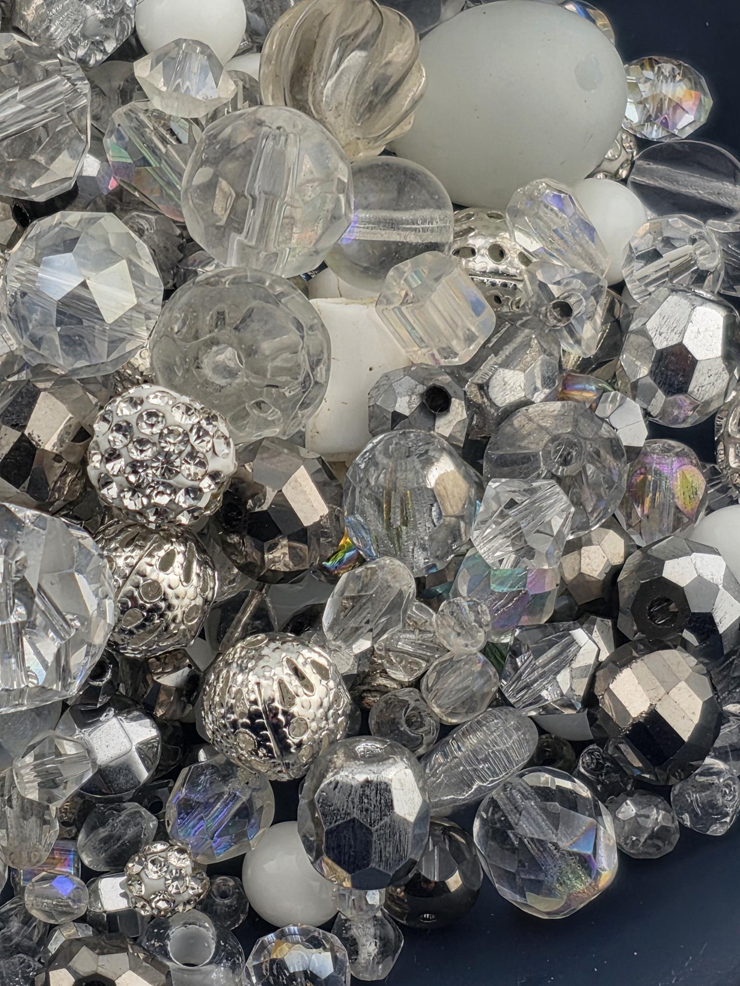 a collection of various glass beads and crystals, including clear, silver, and multicolored glass pieces.