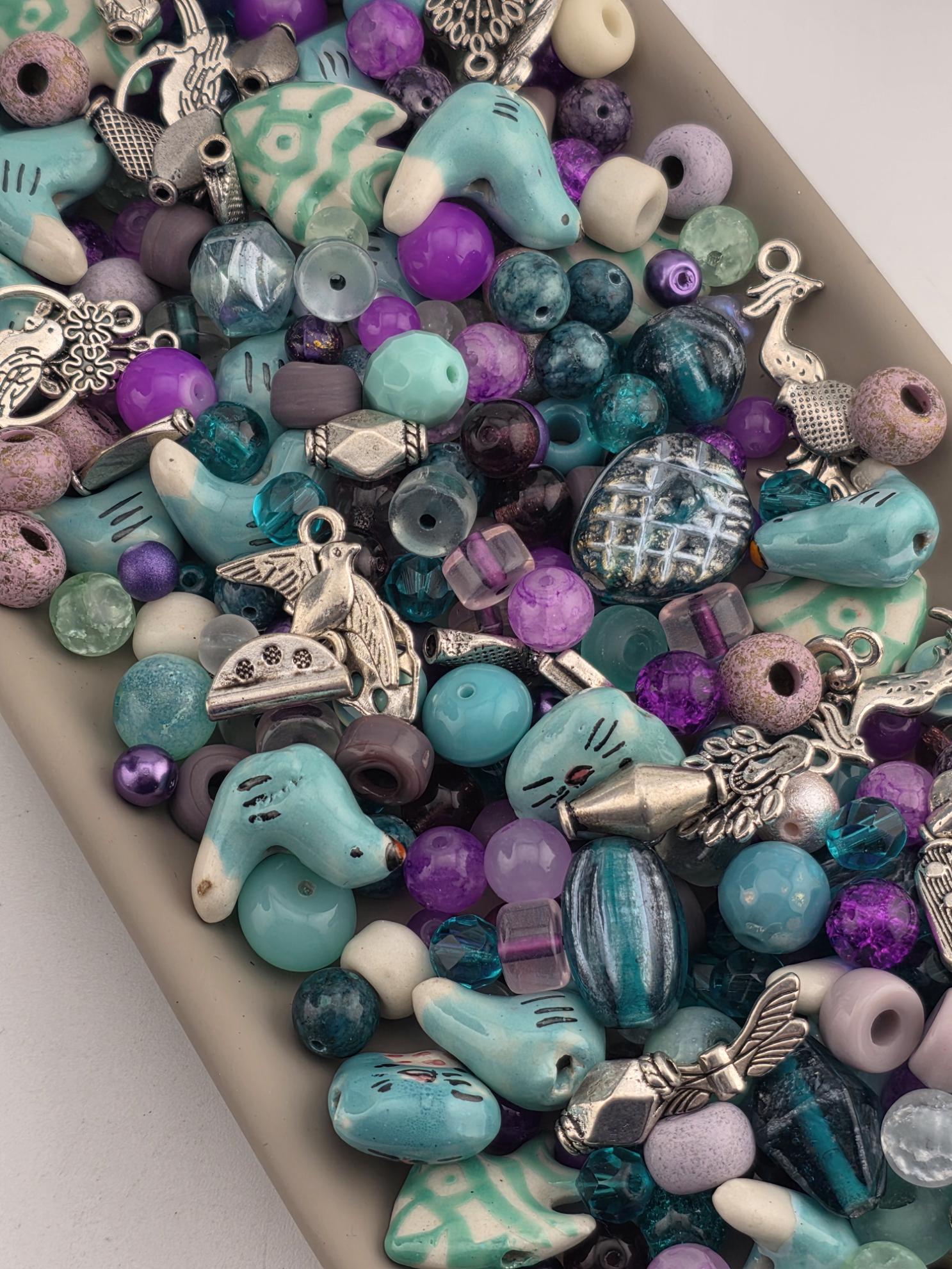 A colorful assortment of beads, charms, and other decorative items in various shades of blue, purple, and green.