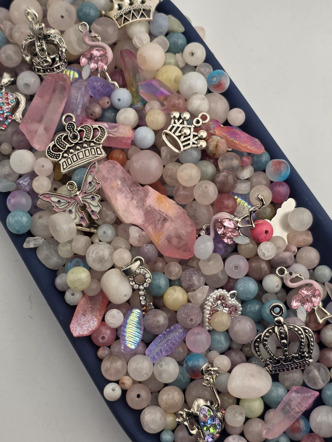 A collection of various beads, charms, and gemstones in a variety of colors and shapes, including crystals, pearls, and gemstones, arranged in a visually appealing manner.