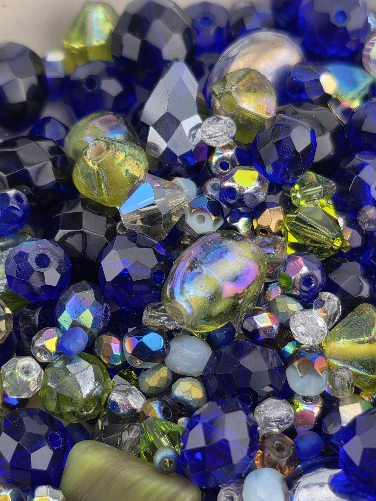 A close-up image of a collection of colorful glass beads, including blue, green, yellow, and silver beads, arranged in a visually appealing manner.